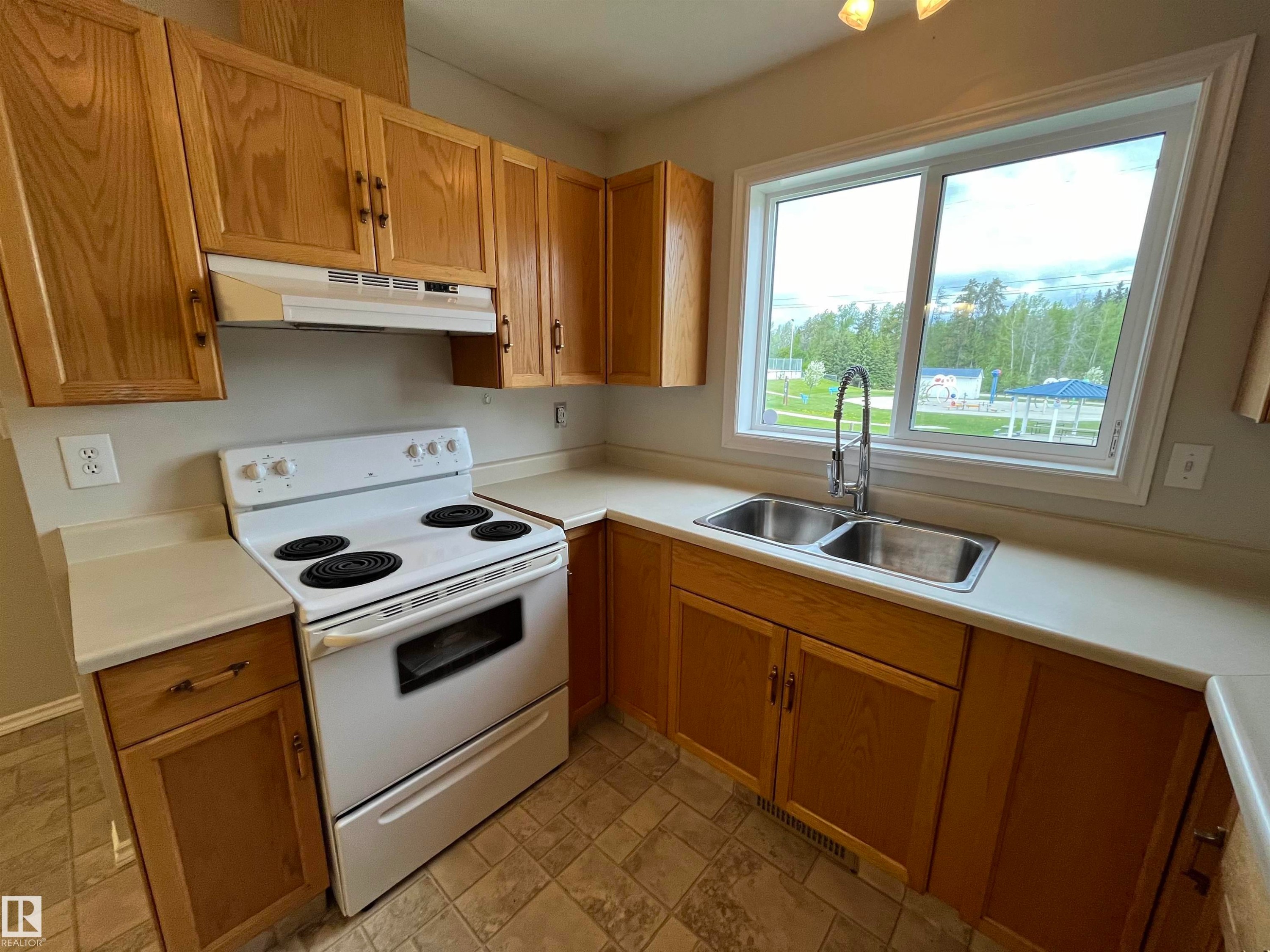 Kitchen with white electric range, light countertops, and stone finish floors - 130 1 Street, Blue Ridge, AB - Indoor Photo Showing Kitchen With Double Sink
