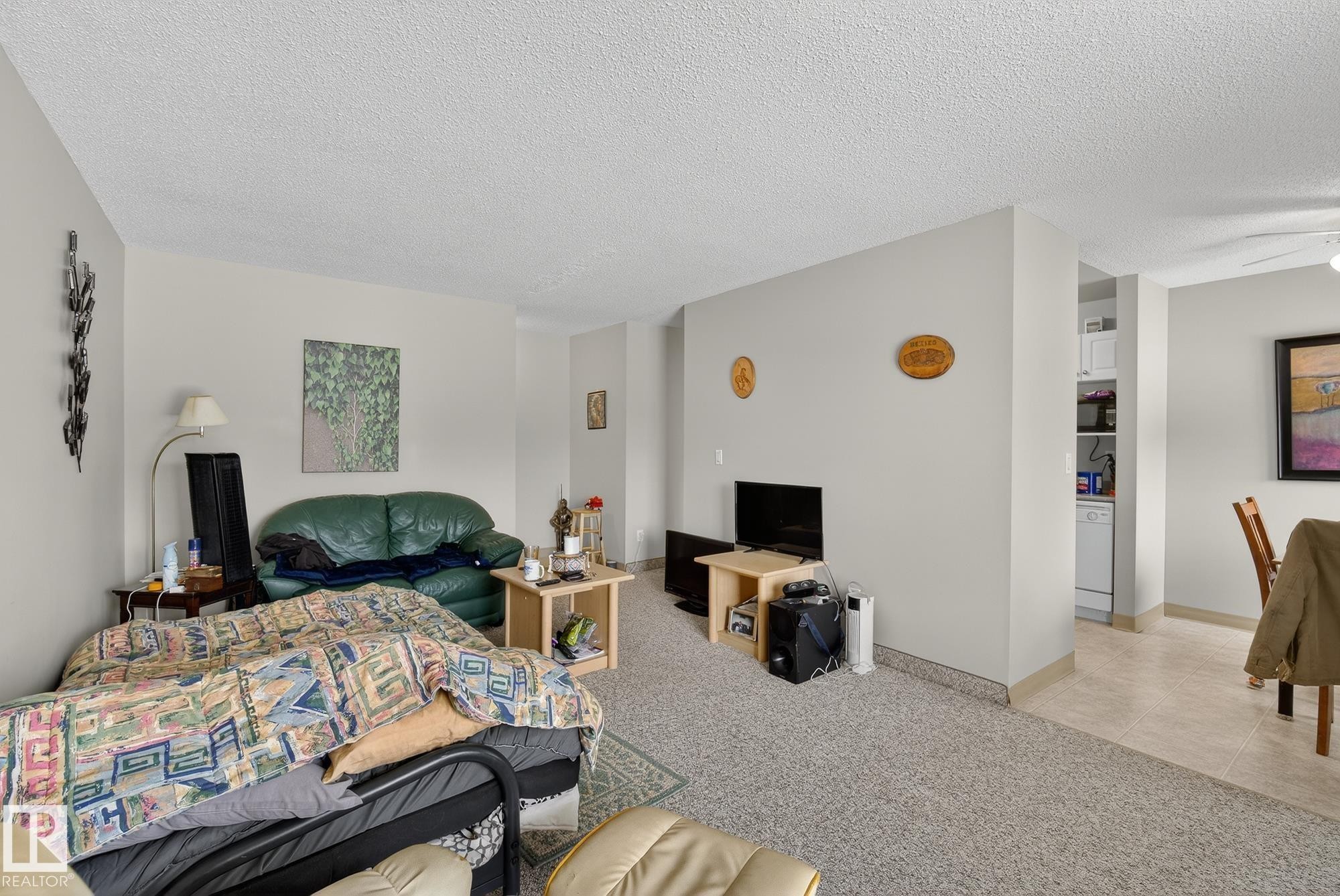 Bedroom featuring light colored carpet, a textured ceiling, and light tile patterned floors - 302 4608 52 Avenue, Stony Plain, AB - Indoor Photo Showing Bedroom