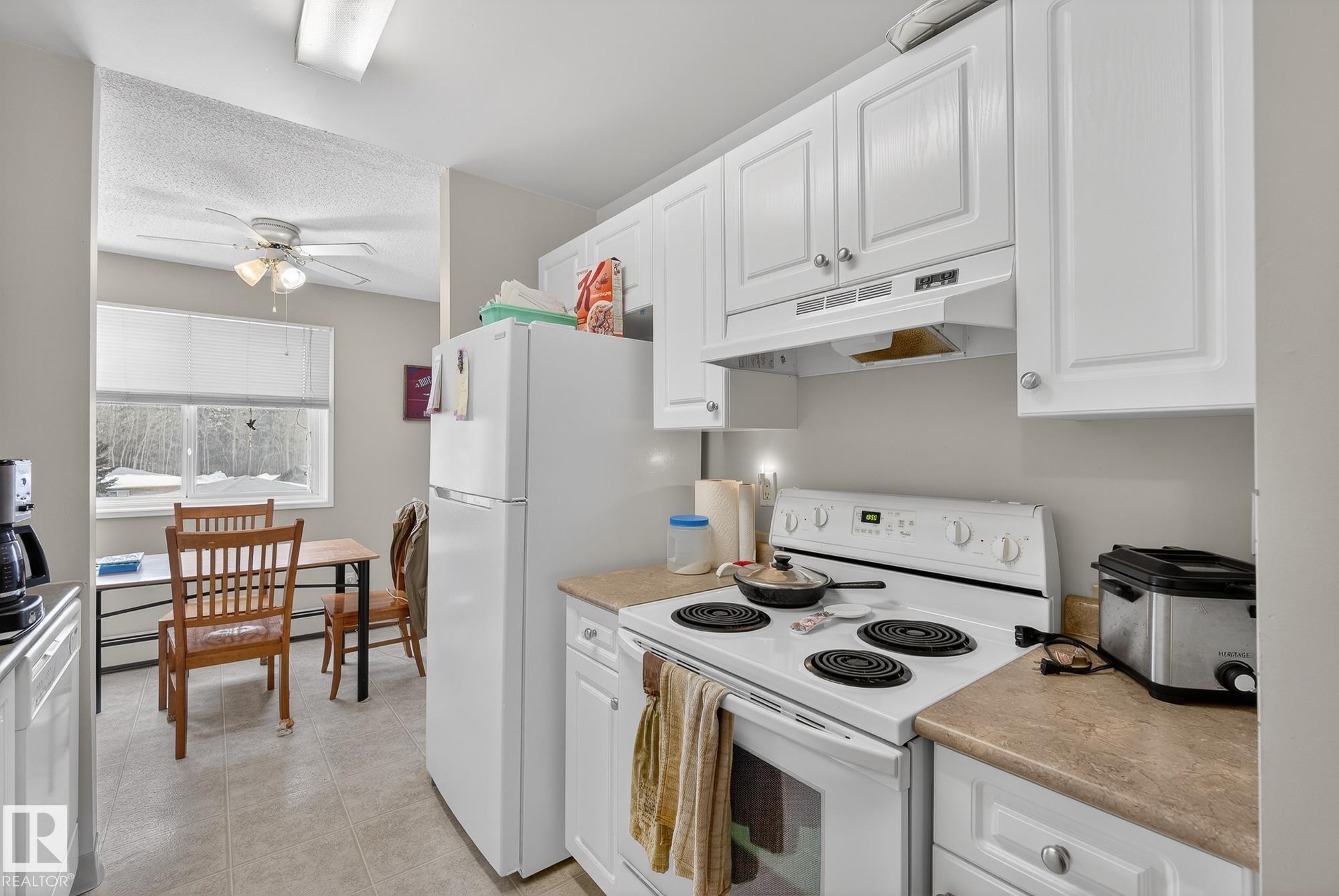 Kitchen with white range with electric cooktop, white cabinetry, light countertops, a ceiling fan, and a textured ceiling - 302 4608 52 Avenue, Stony Plain, AB - Indoor Photo Showing Kitchen