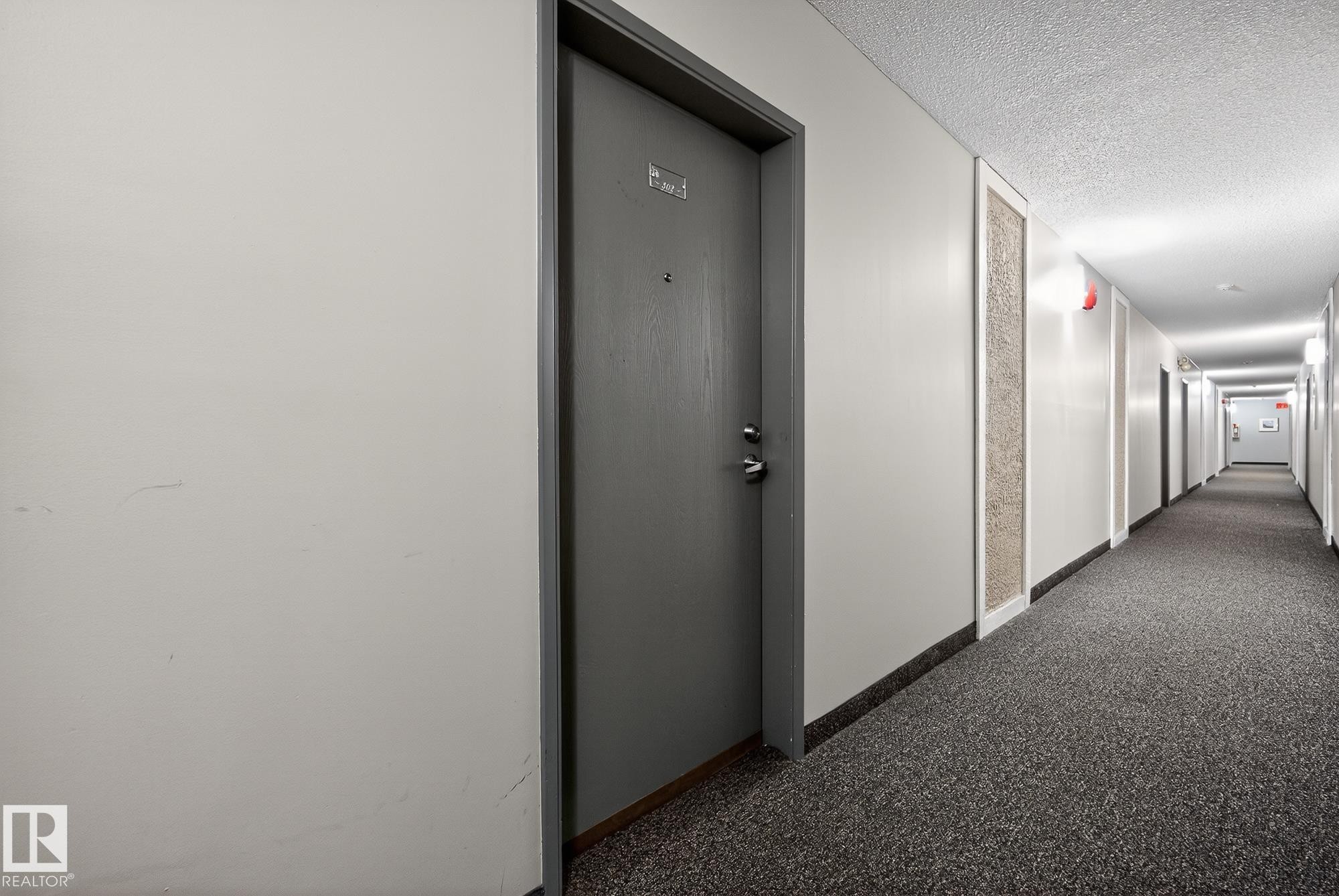 Hallway featuring dark carpet and a textured ceiling - 302 4608 52 Avenue, Stony Plain, AB - Indoor Photo Showing Other Room