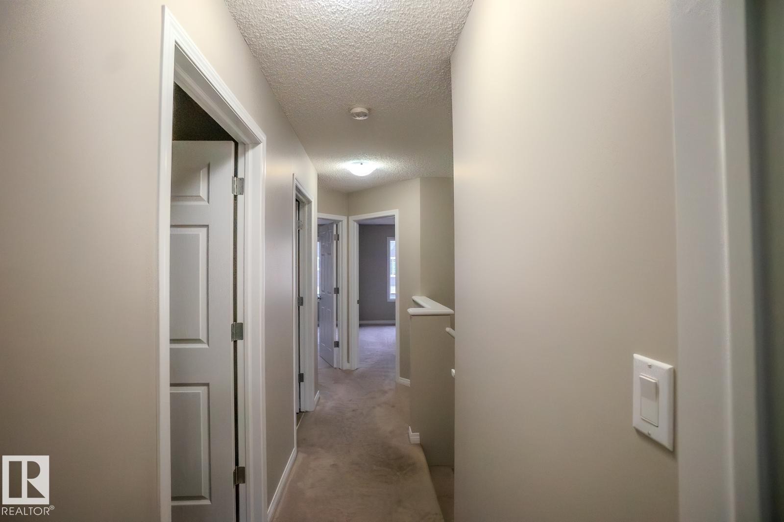 Hall with a textured ceiling and light colored carpet - Edmonton, AB - Indoor Photo Showing Other Room