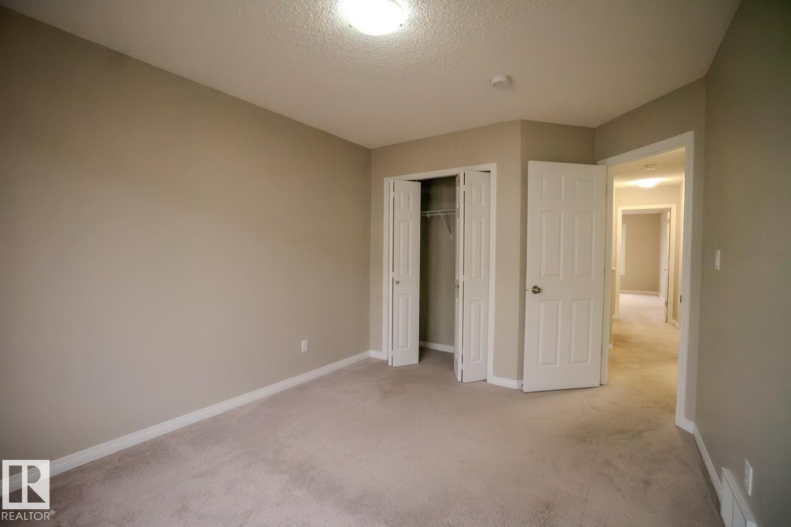 Unfurnished bedroom featuring light colored carpet, a closet, and a textured ceiling - Edmonton, AB - Indoor Photo Showing Other Room