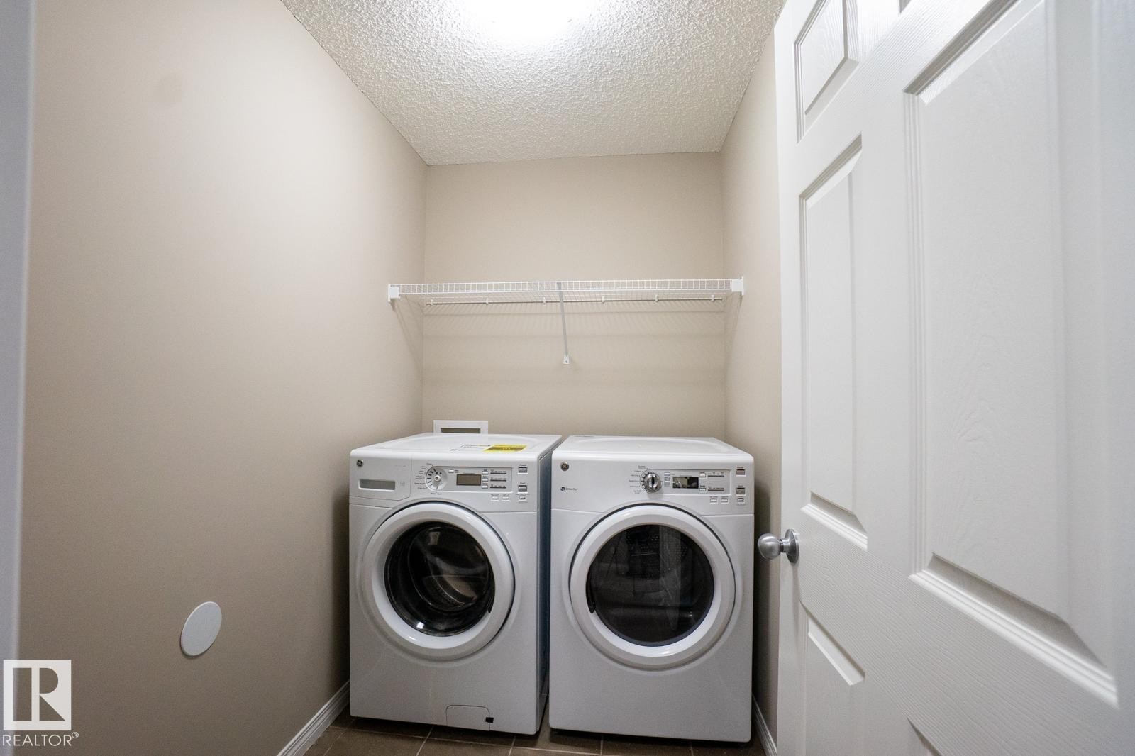 Laundry room with a textured ceiling, separate washer and dryer, and tile patterned floors - Edmonton, AB - Indoor Photo Showing Laundry Room