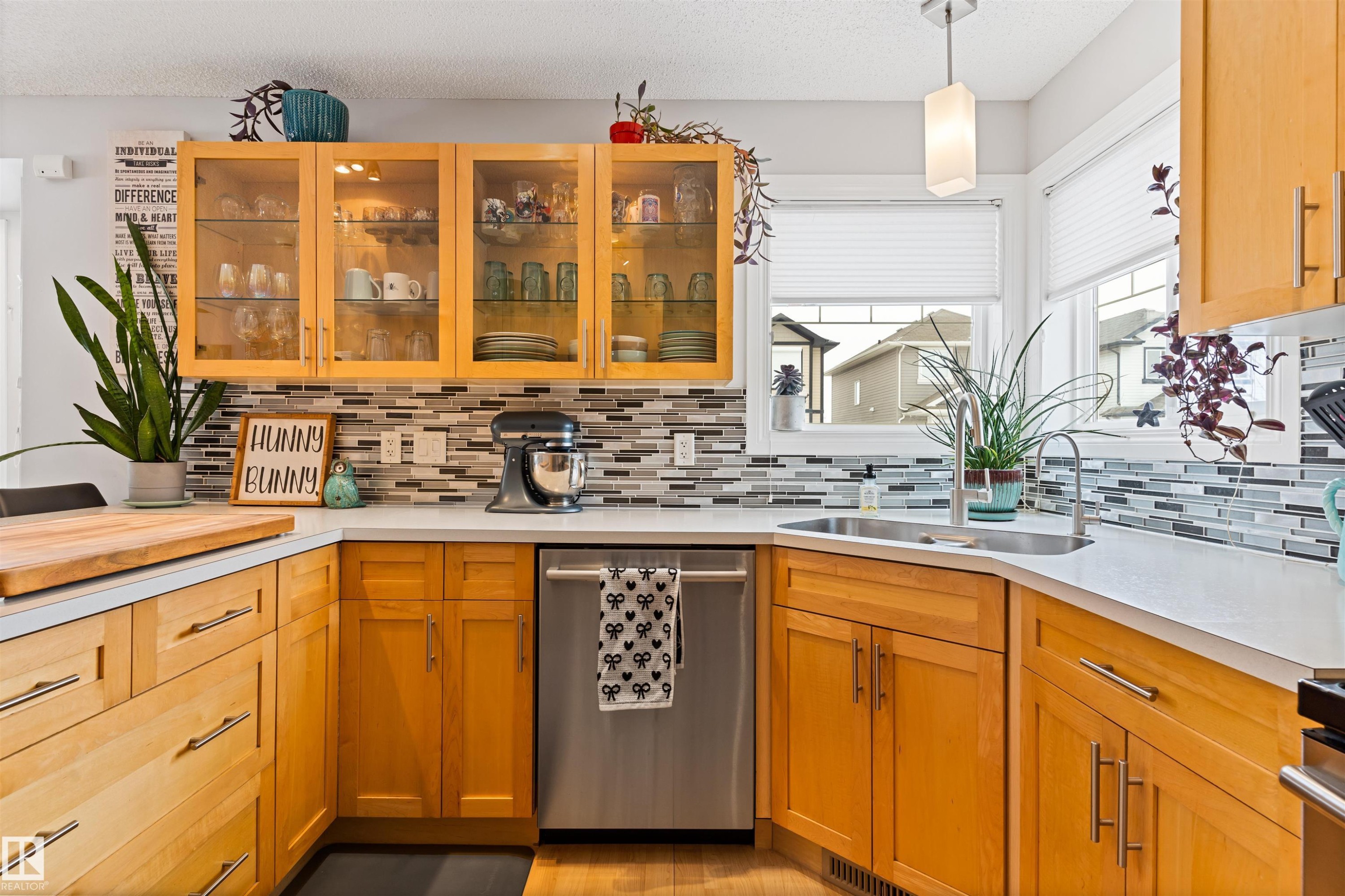 Kitchen featuring stainless steel dishwasher, decorative light fixtures, glass fronted cabinets, decorative backsplash, and a textured ceiling - 7804 Schmid Place, Edmonton, AB - Indoor Photo Showing Kitchen With Double Sink