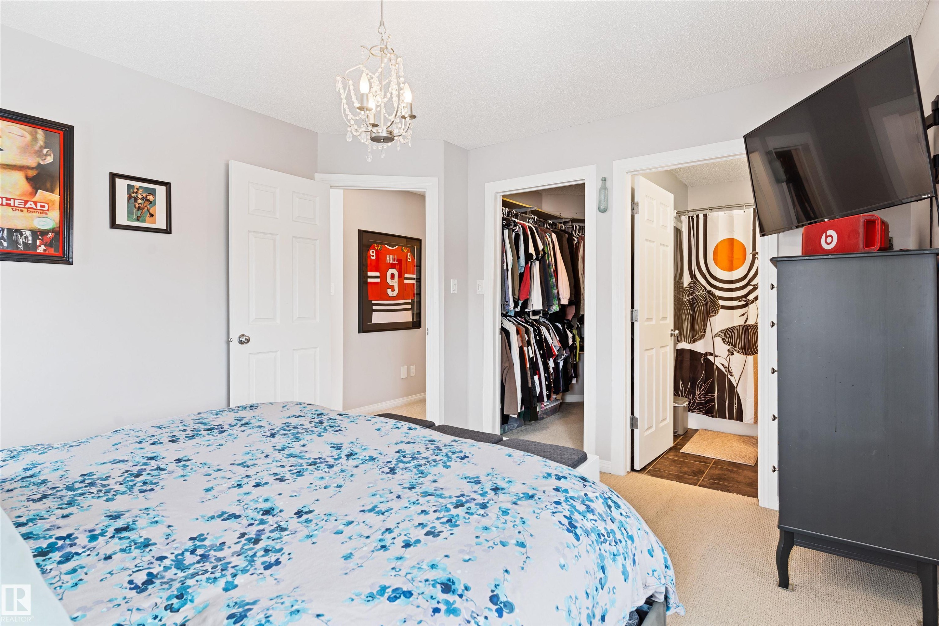 Bedroom with ensuite bath, suspended lighting, light carpet, and a walk in closet - 7804 Schmid Place, Edmonton, AB - Indoor Photo Showing Bedroom