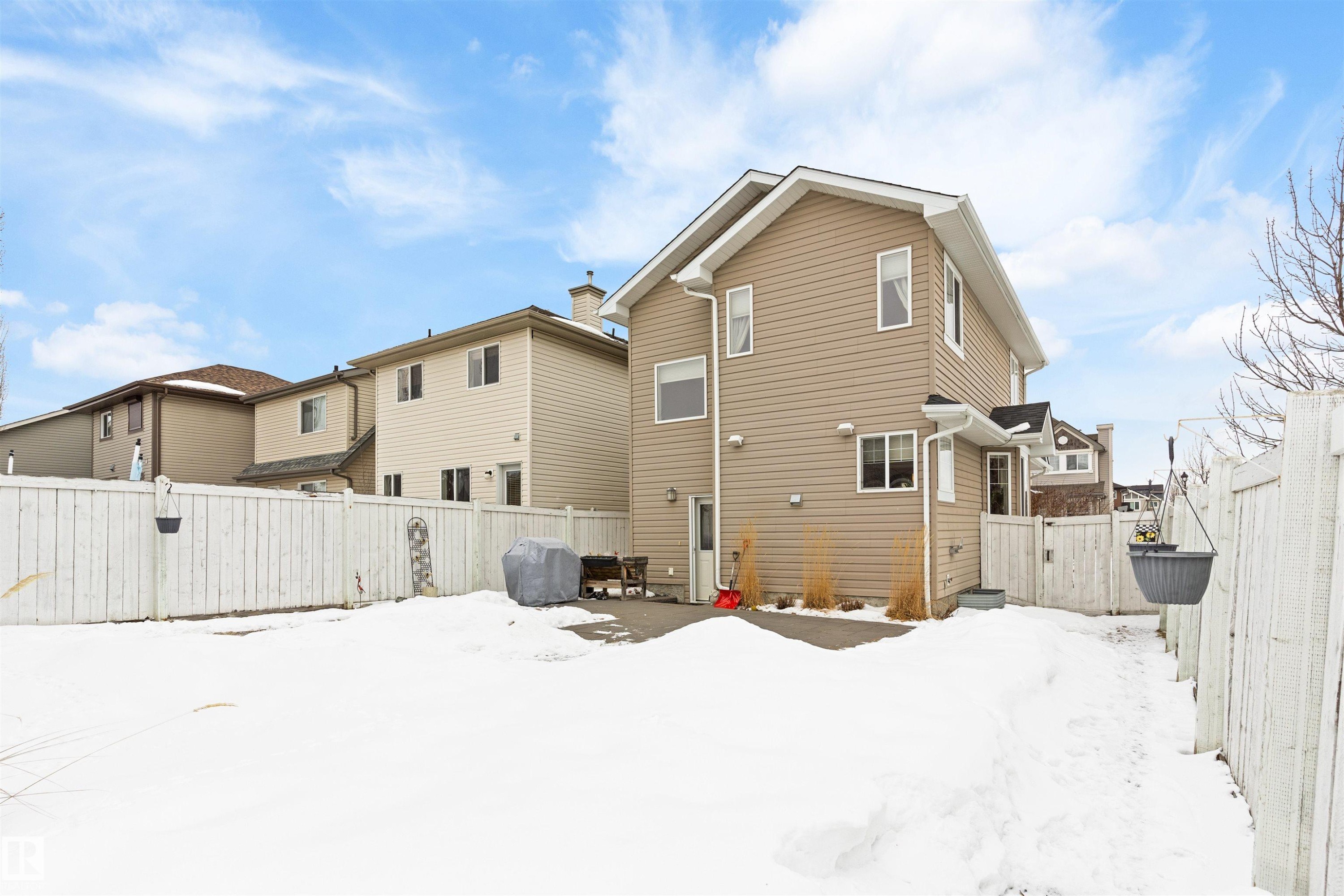 Snow covered house featuring a fenced backyard, a gate, and a patio - 7804 Schmid Place, Edmonton, AB - Outdoor With Exterior