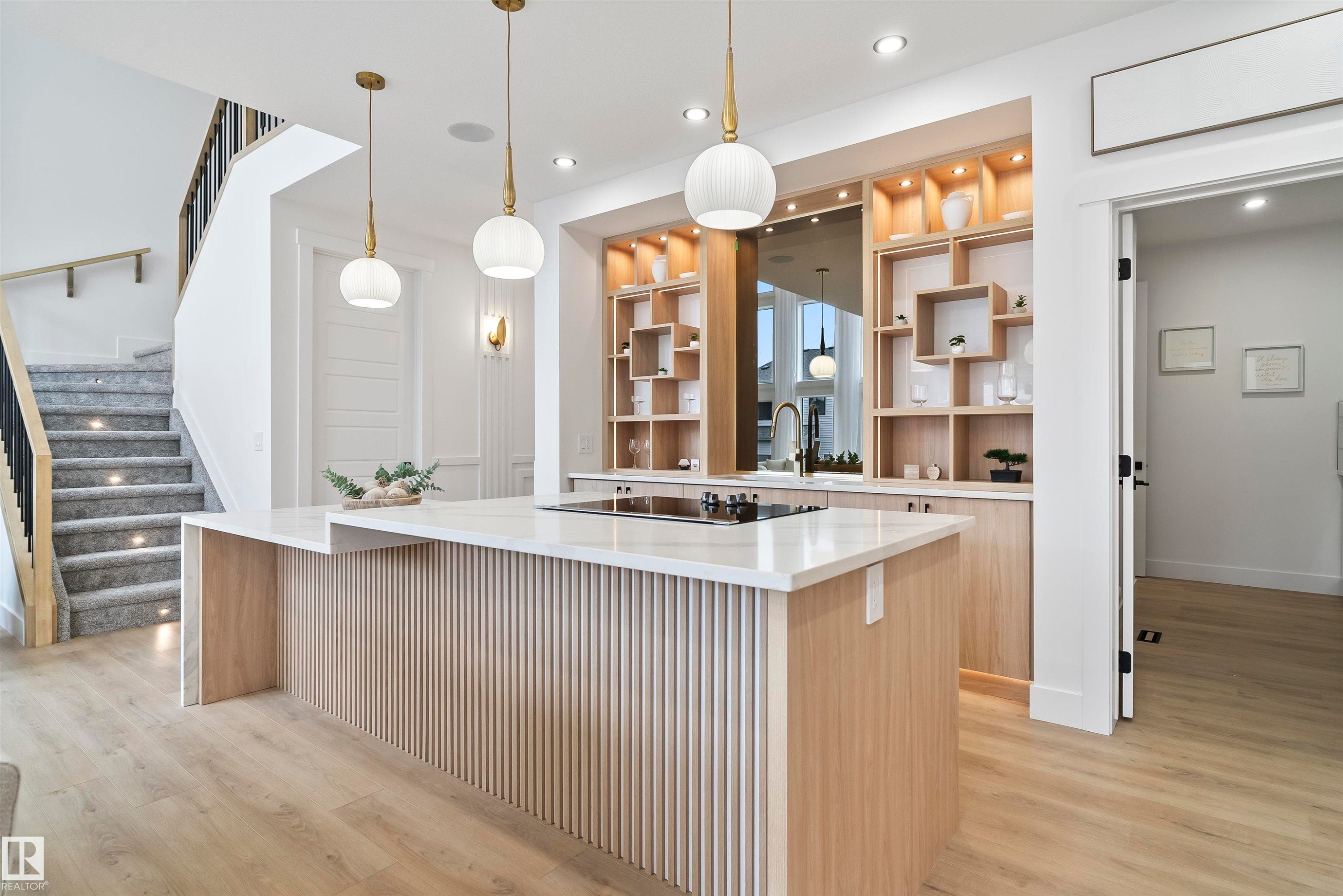 Kitchen featuring light wood finish cabinets, light wood-style flooring, decorative light fixtures, a spacious island, and light stone countertops - 13152 187 Avenue, Edmonton, AB - Indoor Photo Showing Kitchen With Upgraded Kitchen