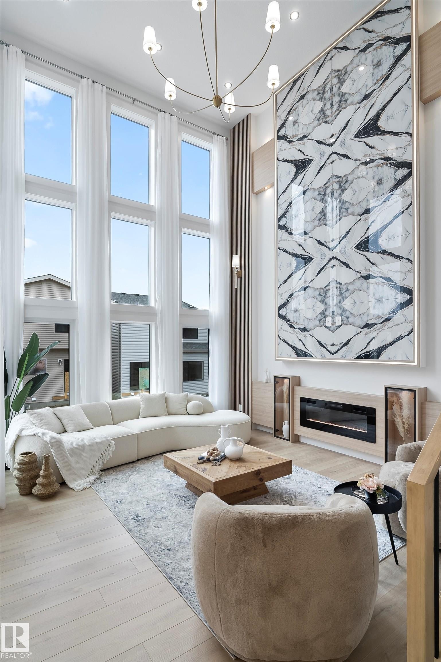 Living room with a glass covered fireplace, a high ceiling, light wood-style floors, and healthy amount of natural light - 13152 187 Avenue, Edmonton, AB - Indoor Photo Showing Living Room With Fireplace