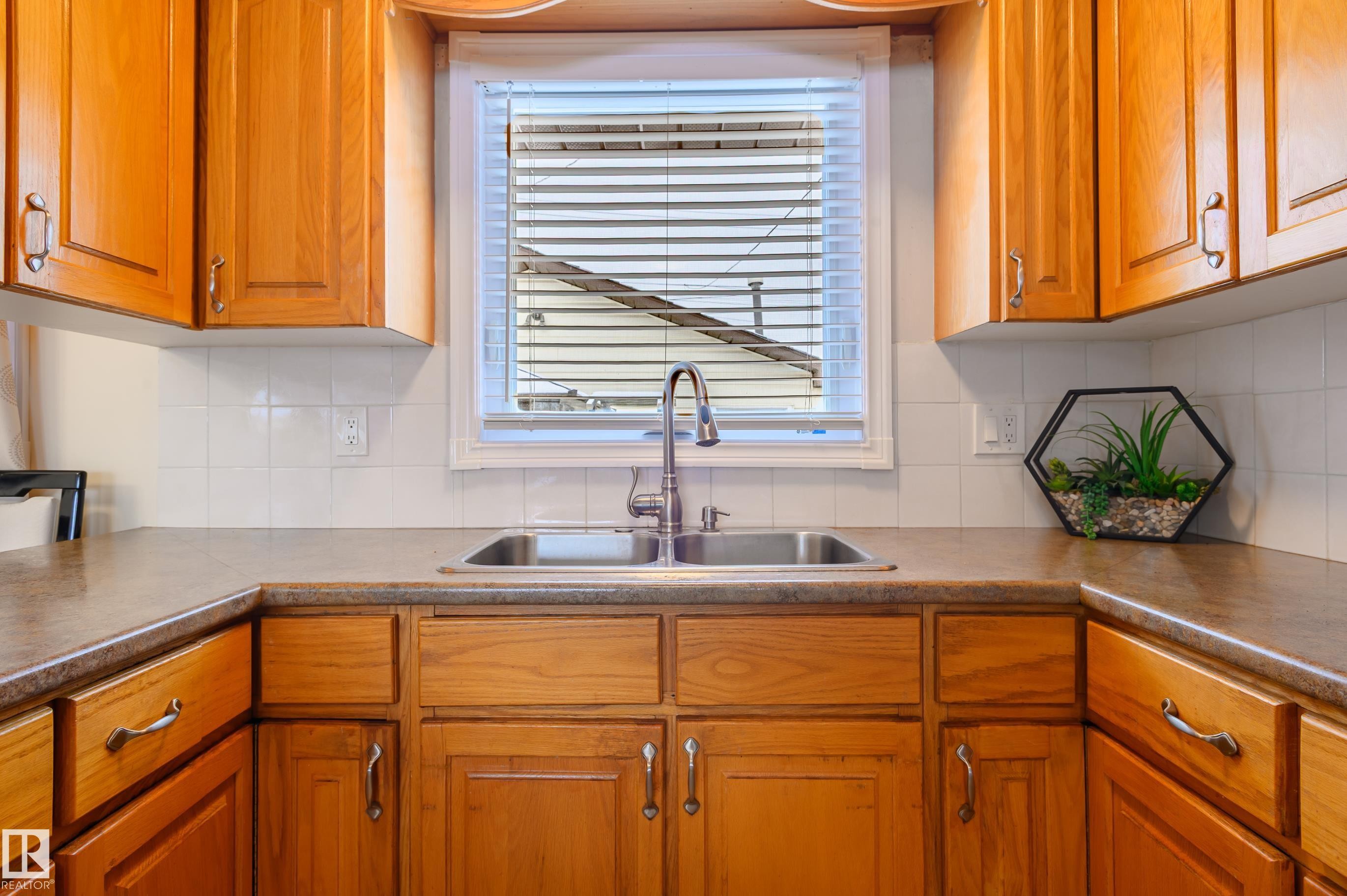 Kitchen with wood finish cabinetry, backsplash, and dark countertops - 13420 113A St, Edmonton, AB - Indoor Photo Showing Kitchen With Double Sink