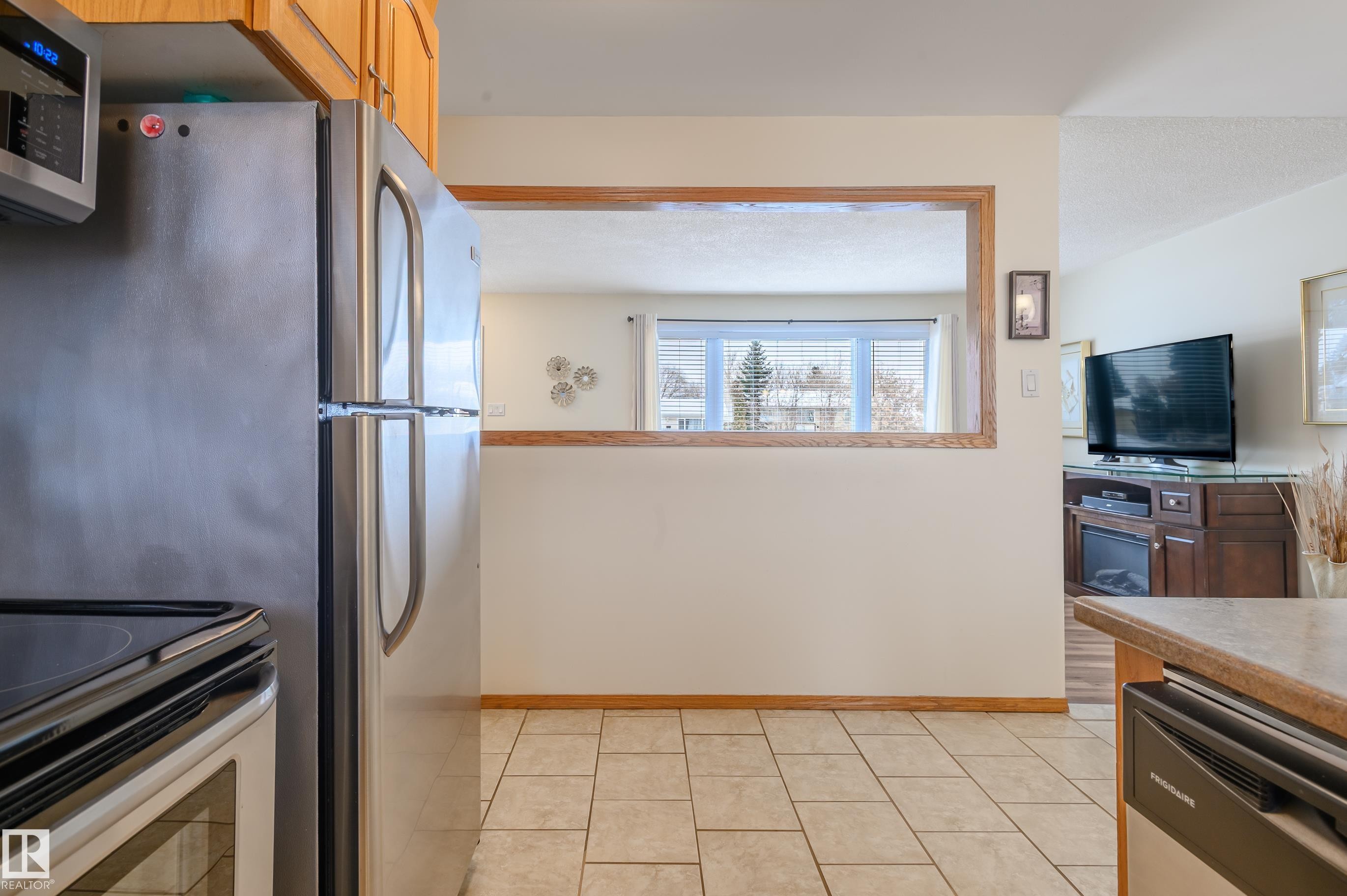 Kitchen featuring stainless steel appliances, light tile patterned flooring, and wood finish cabinets - 13420 113A St, Edmonton, AB - Indoor Photo Showing Kitchen