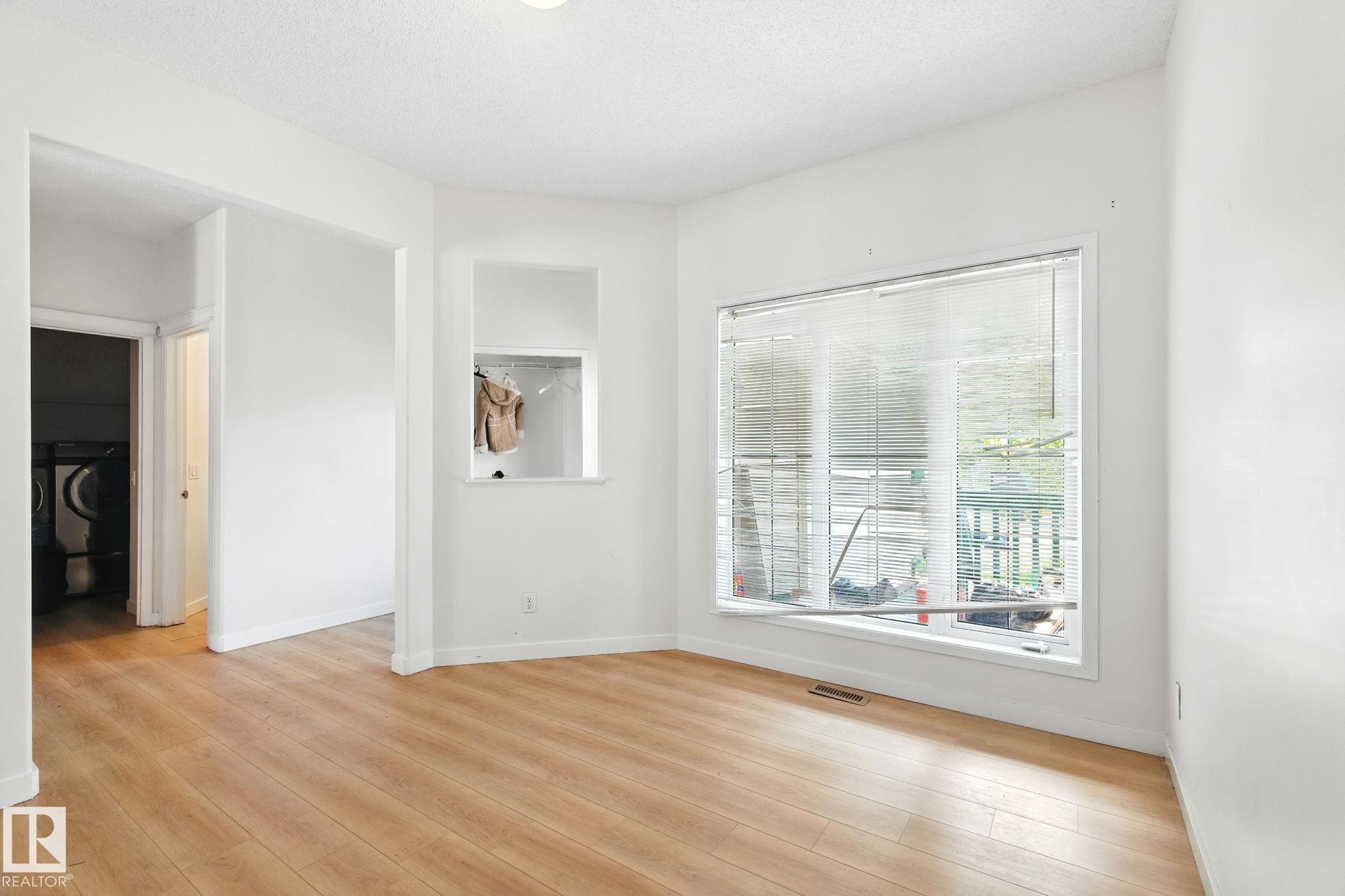 Empty room featuring light wood-style flooring, washer / clothes dryer, and a textured ceiling - 7836 7 Avenue, Edmonton, AB - Indoor Photo Showing Other Room