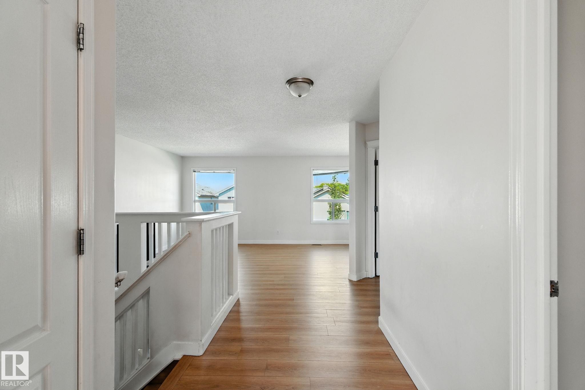 Corridor featuring a textured ceiling, light wood-style floors, and an upstairs landing - 7836 7 Avenue, Edmonton, AB - Indoor Photo Showing Other Room