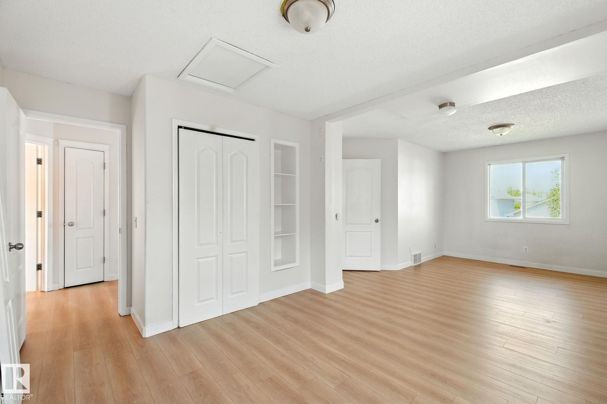 Unfurnished bedroom with light wood finished floors, a textured ceiling, and a closet - 7836 7 Avenue, Edmonton, AB - Indoor Photo Showing Other Room