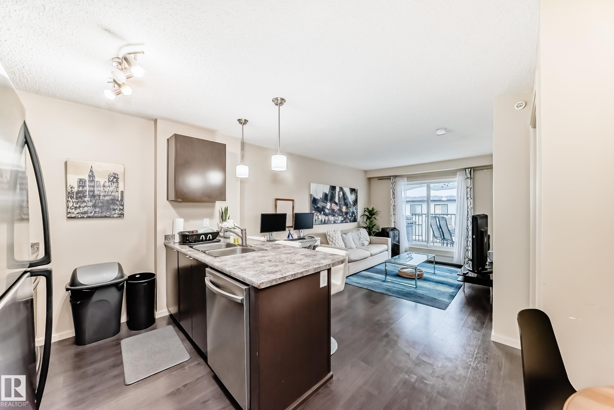 Kitchen featuring open floor plan, light countertops, a peninsula, dark wood finish cabinetry, and stainless steel appliances - 403 340 Windermere Road, Edmonton, AB - Indoor