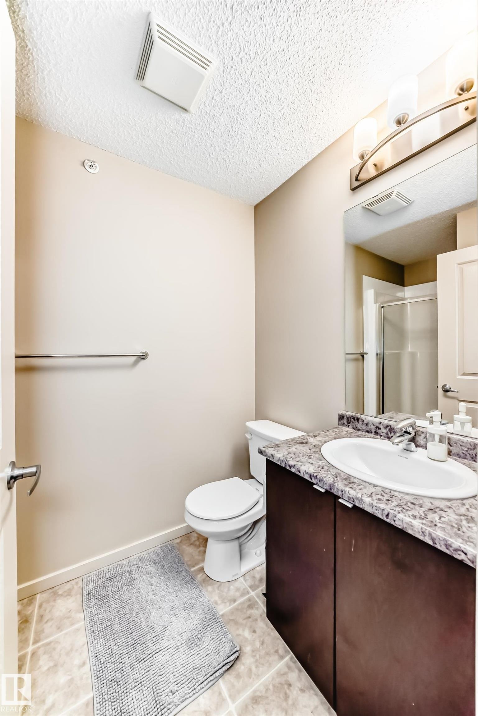 Full bathroom featuring vanity, a textured ceiling, and a shower stall - 403 340 Windermere Road, Edmonton, AB - Indoor Photo Showing Bathroom