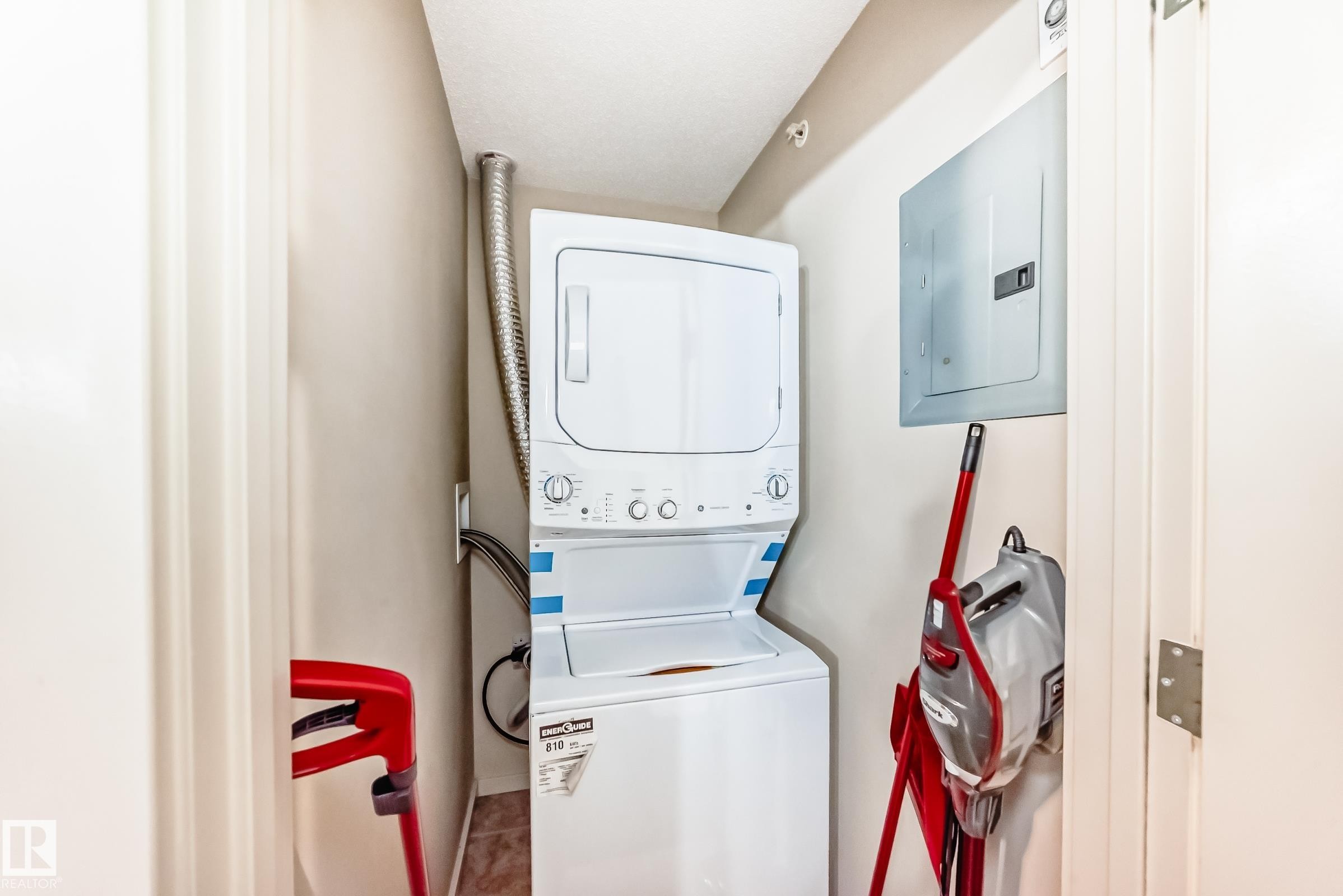 Laundry area featuring electric panel and stacked washer and dryer - 403 340 Windermere Road, Edmonton, AB - Indoor Photo Showing Laundry Room