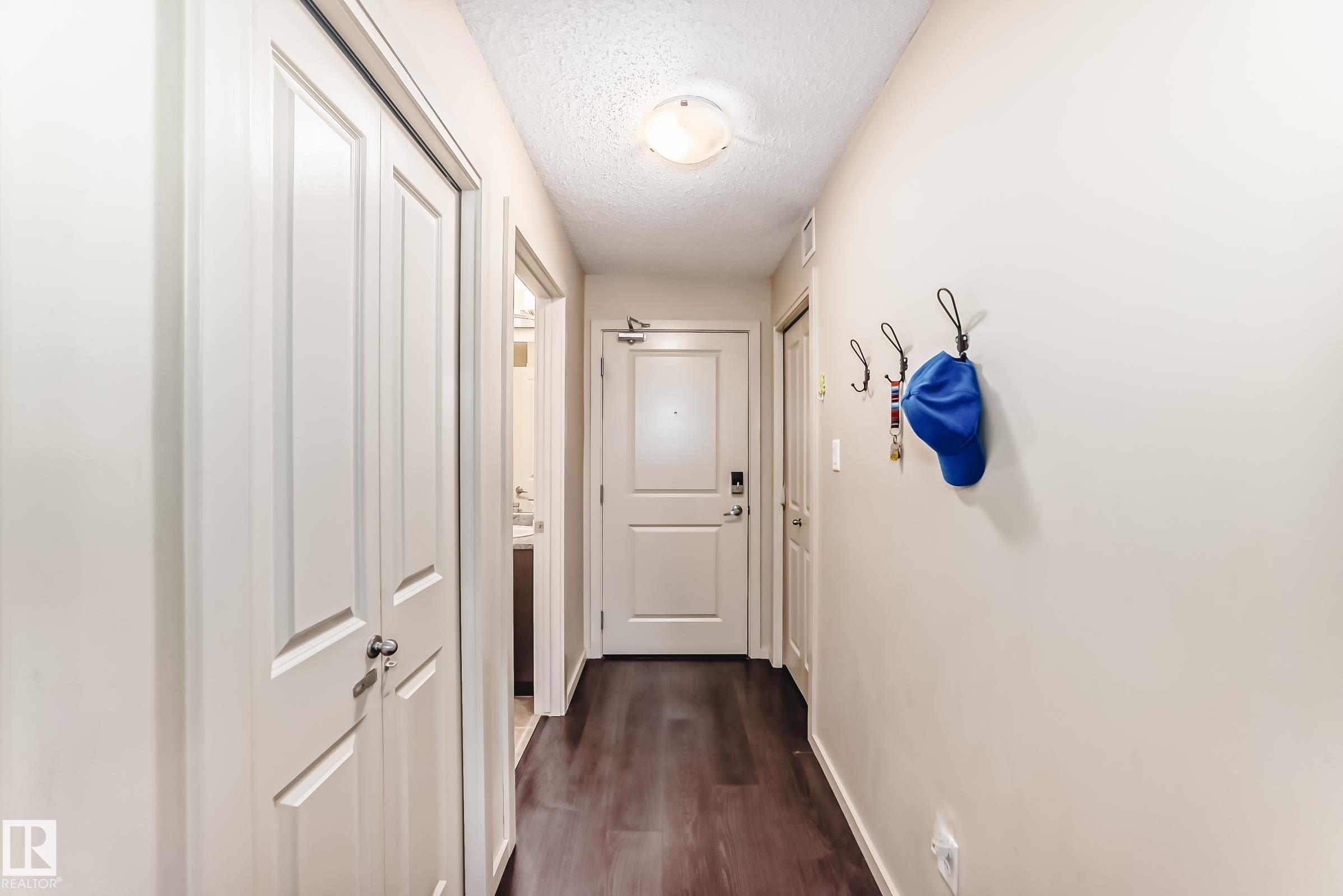 Hallway featuring a textured ceiling and dark wood-style floors - 403 340 Windermere Road, Edmonton, AB - Indoor Photo Showing Other Room