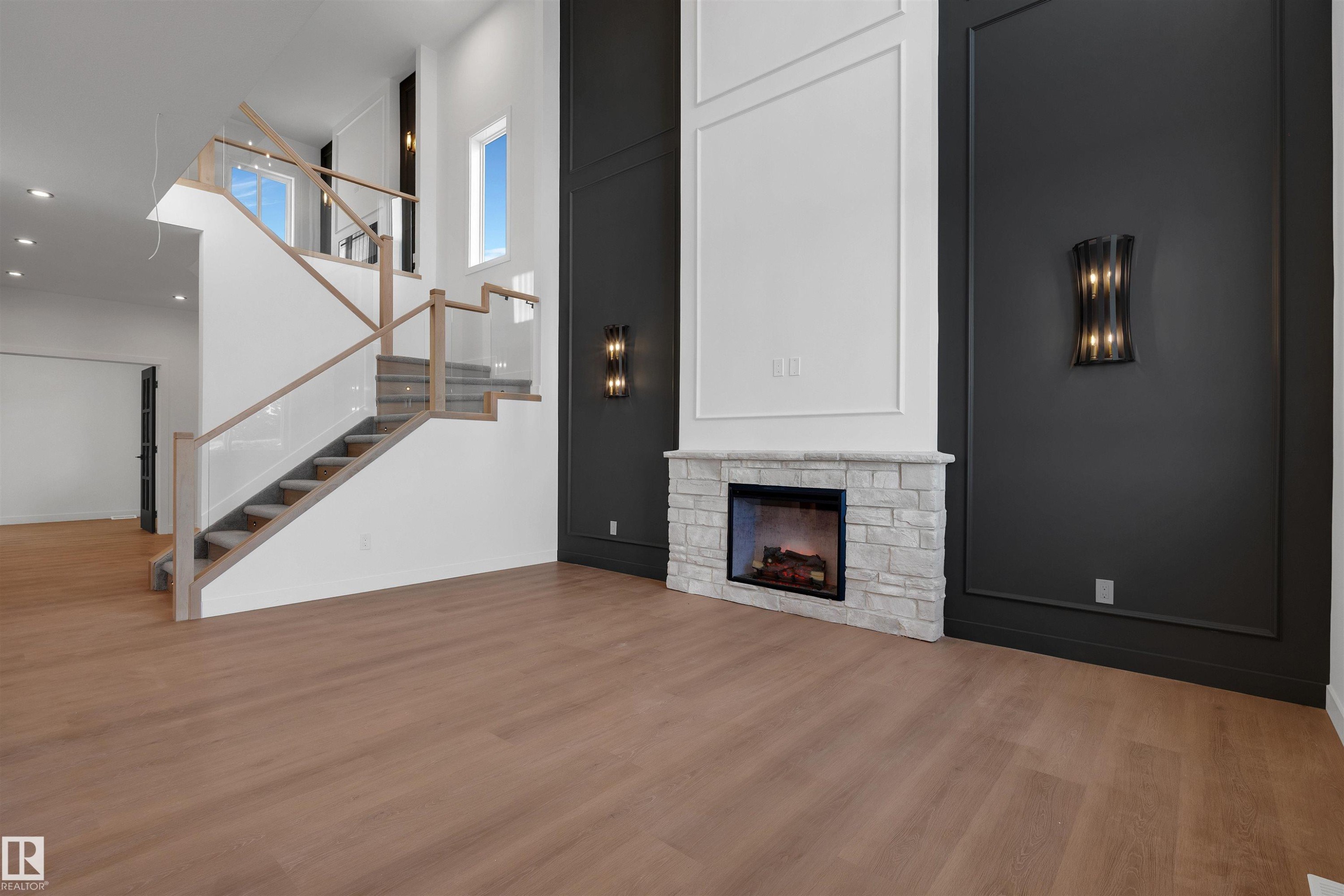 Unfurnished living room with a high ceiling, a fireplace, light wood finished floors, recessed lighting, and stairway - 34 Grayson Green, Stony Plain, AB - Indoor With Fireplace