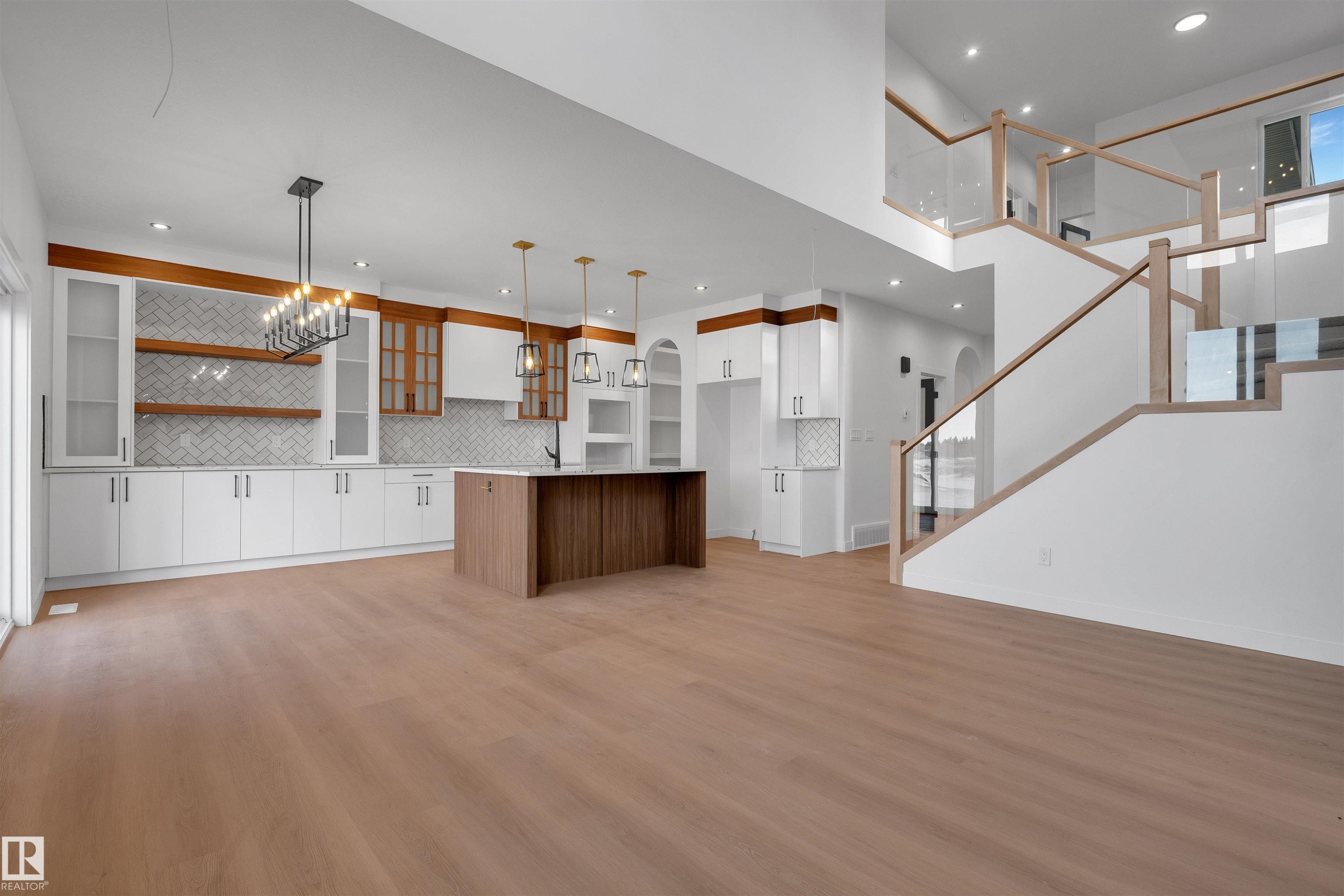 Kitchen with open floor plan, white cabinetry, brown cabinetry, an island with sink, and pendant lighting - 34 Grayson Green, Stony Plain, AB - Indoor Photo Showing Kitchen