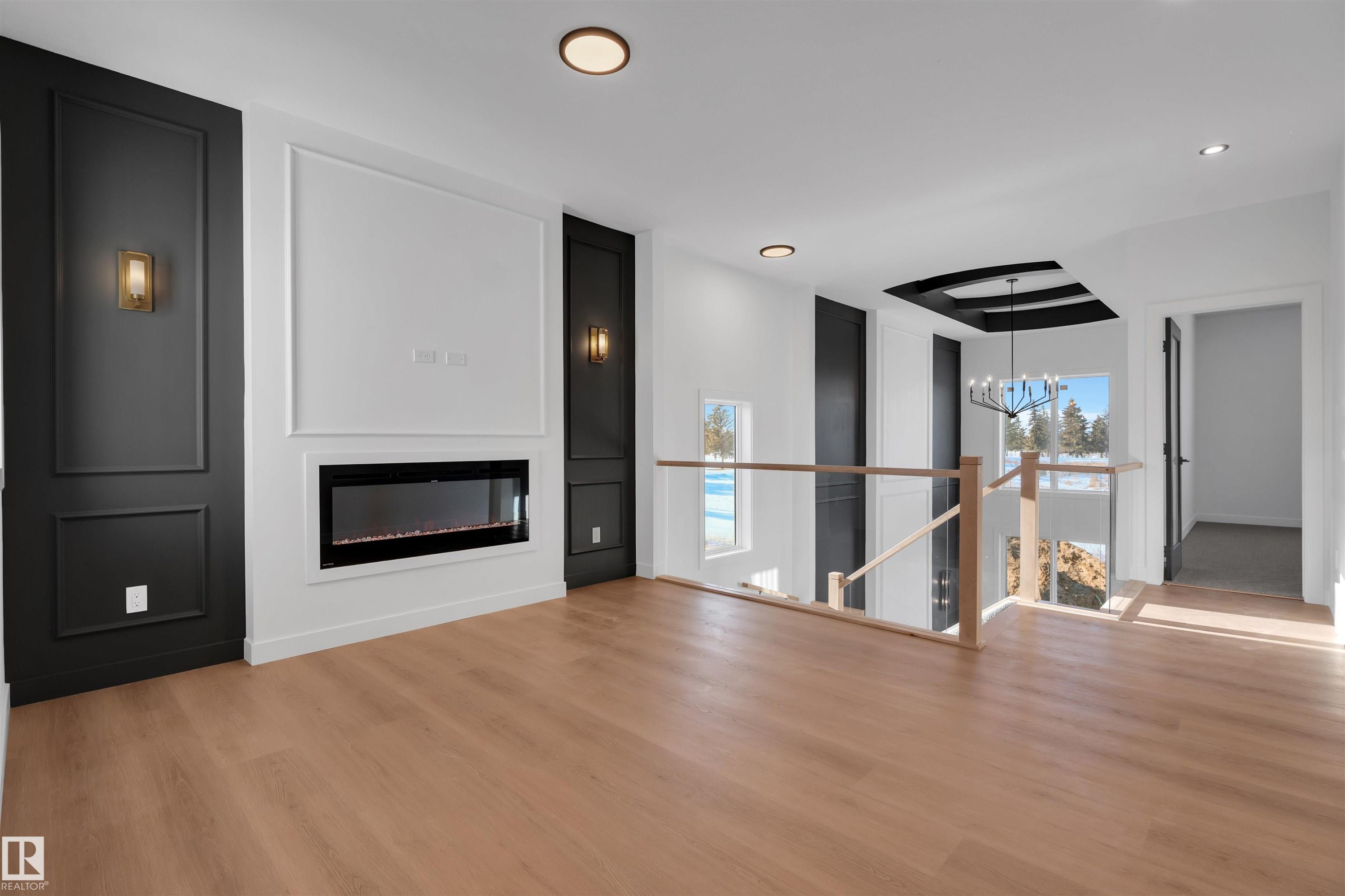 Unfurnished living room with a glass covered fireplace, a chandelier, light wood-type flooring, and recessed lighting - 34 Grayson Green, Stony Plain, AB - Indoor Photo Showing Living Room With Fireplace