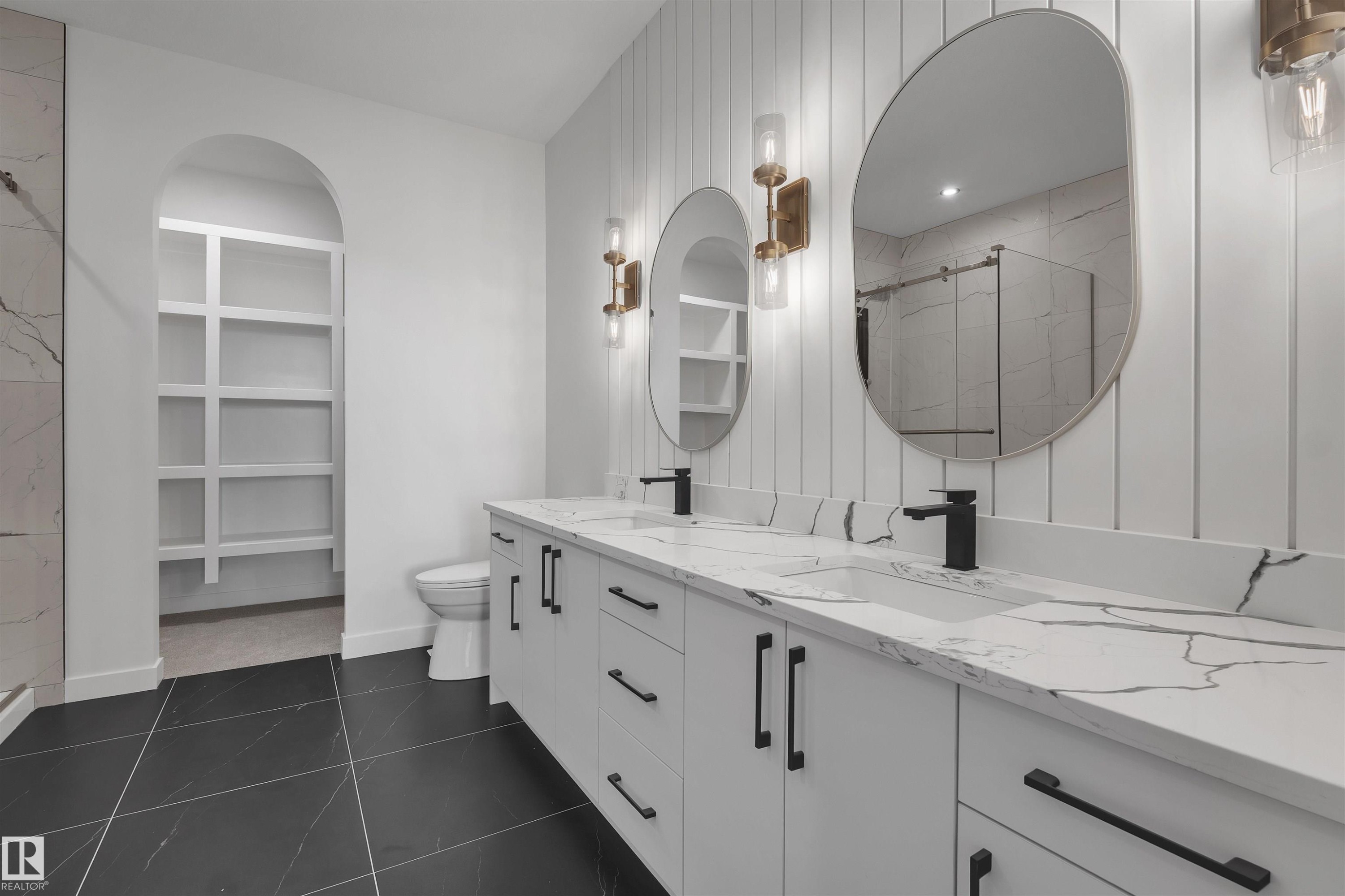 Full bathroom featuring a marble finish shower, double vanity, and dark tile patterned floors - 34 Grayson Green, Stony Plain, AB - Indoor Photo Showing Bathroom