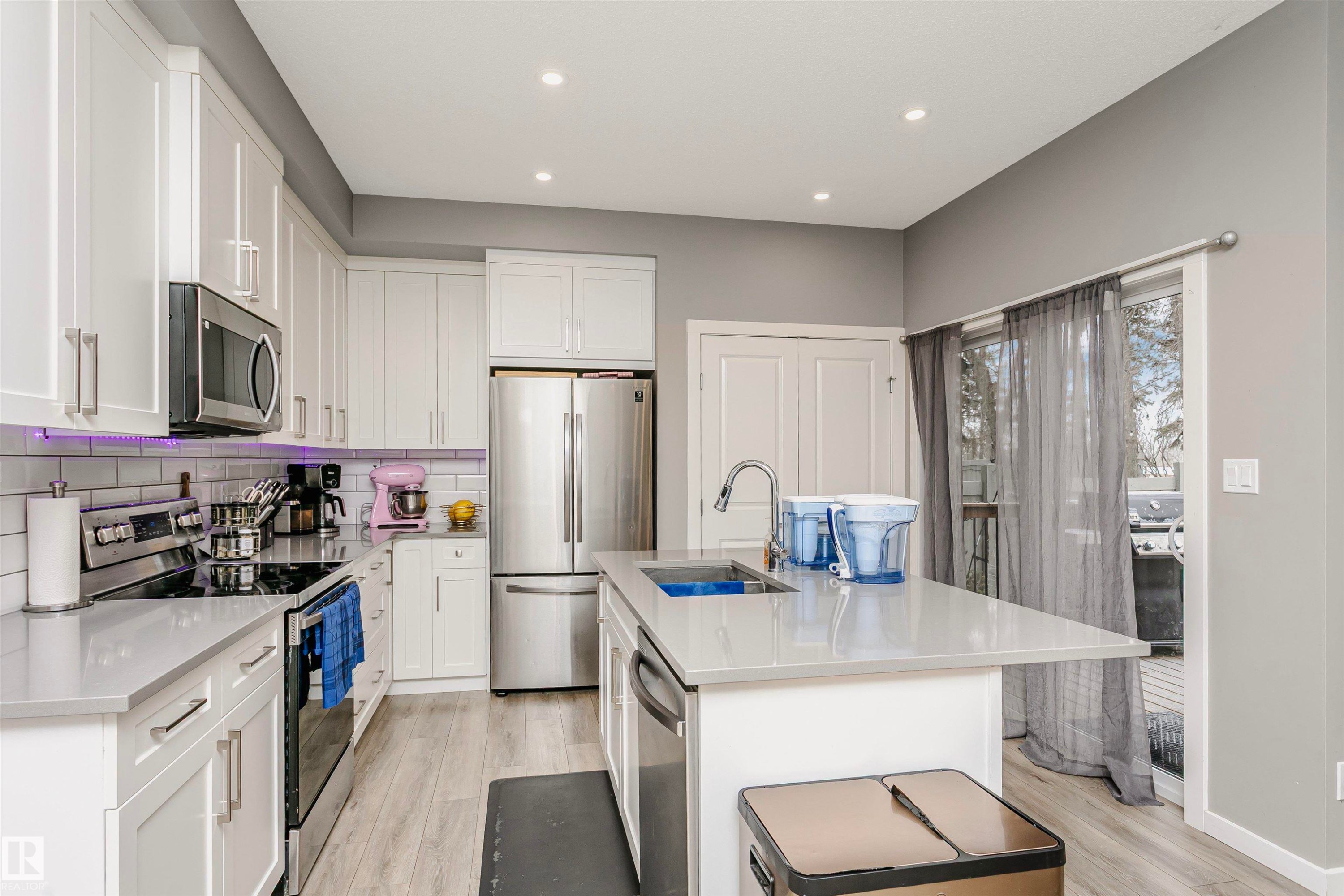 Kitchen featuring stainless steel appliances, a center island with sink, white cabinetry, light wood finished floors, and recessed lighting - 7322 Chivers Crescent, Edmonton, AB - Indoor Photo Showing Kitchen With Double Sink With Upgraded Kitchen