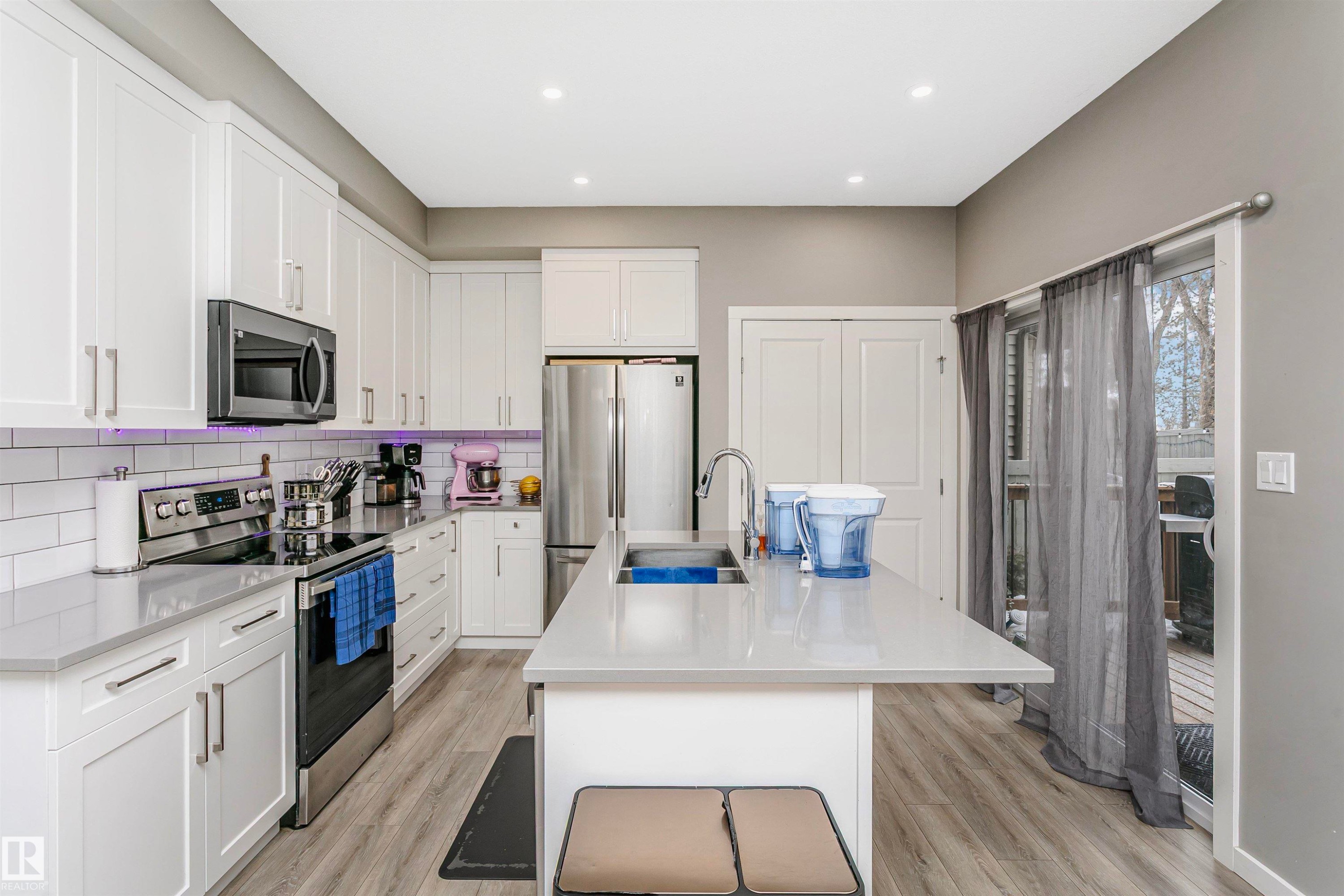 Kitchen featuring stainless steel appliances, white cabinets, an island with sink, light wood-style floors, and recessed lighting - 7322 Chivers Crescent, Edmonton, AB - Indoor Photo Showing Kitchen With Upgraded Kitchen
