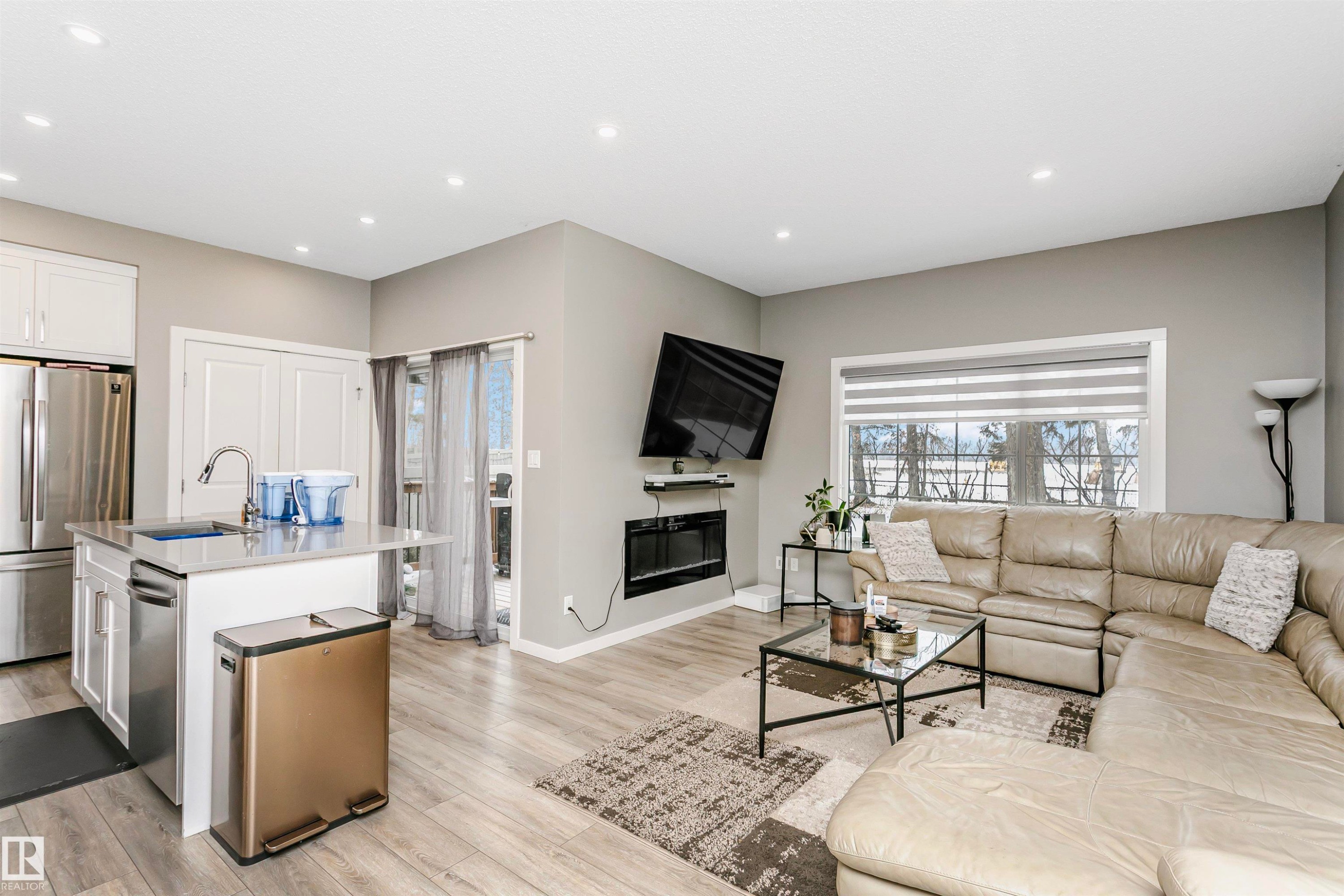Living room with a glass covered fireplace, light wood-type flooring, recessed lighting, and healthy amount of natural light - 7322 Chivers Crescent, Edmonton, AB - Indoor Photo Showing Living Room
