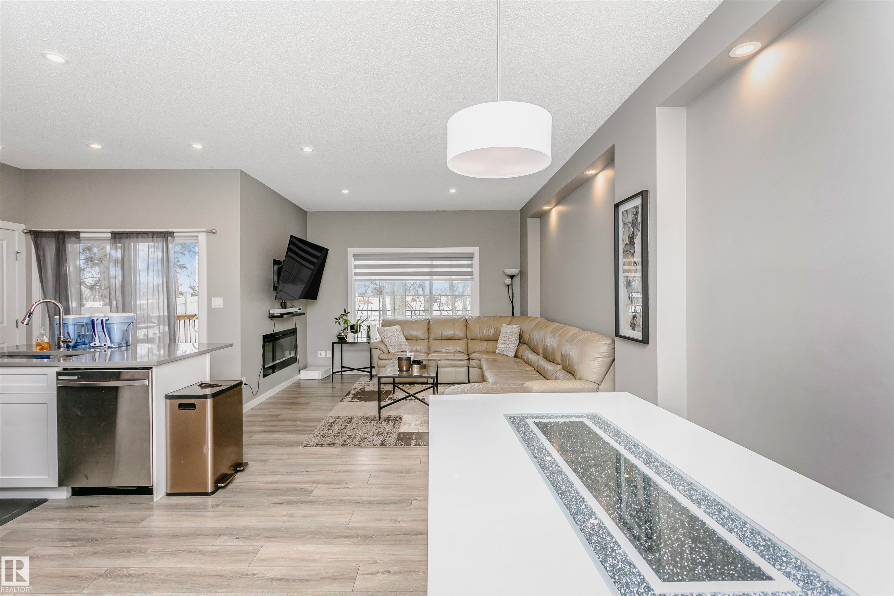 Living room with light wood-type flooring, a glass covered fireplace, and recessed lighting - 7322 Chivers Crescent, Edmonton, AB - Indoor