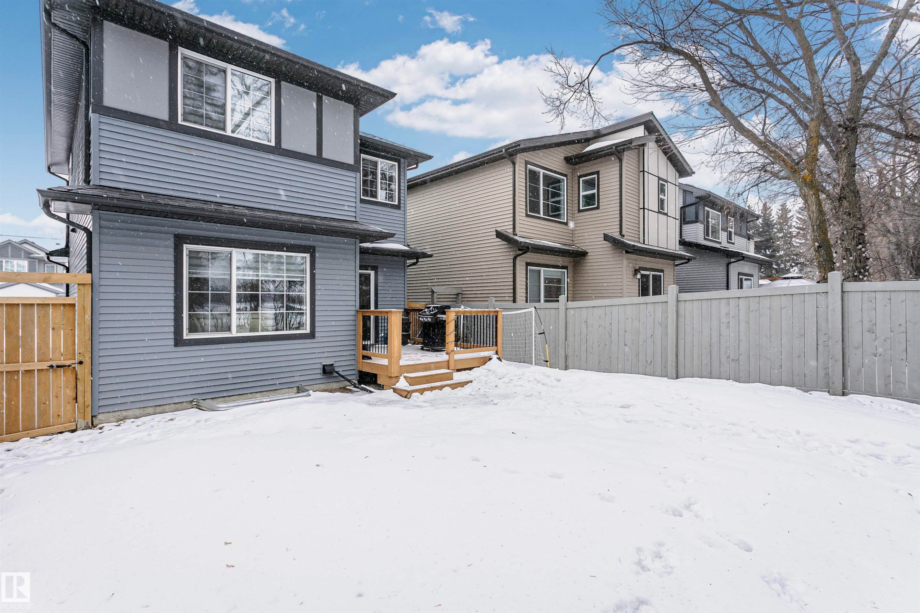 Snow covered house with a fenced backyard, a deck, and a gate - 7322 Chivers Crescent, Edmonton, AB - Outdoor