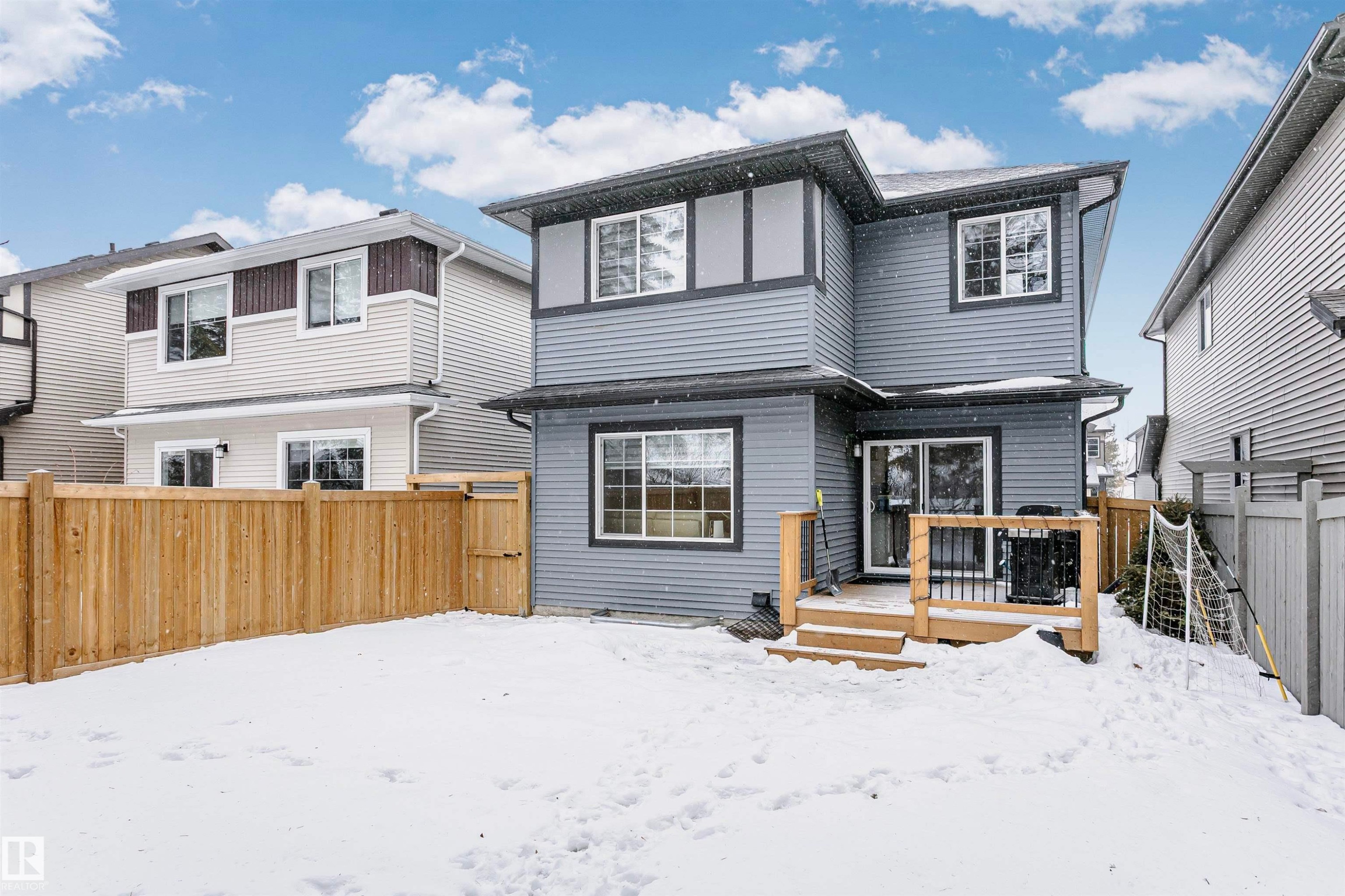 Snow covered house with a fenced backyard, a deck, and a gate - 7322 Chivers Crescent, Edmonton, AB - Outdoor
