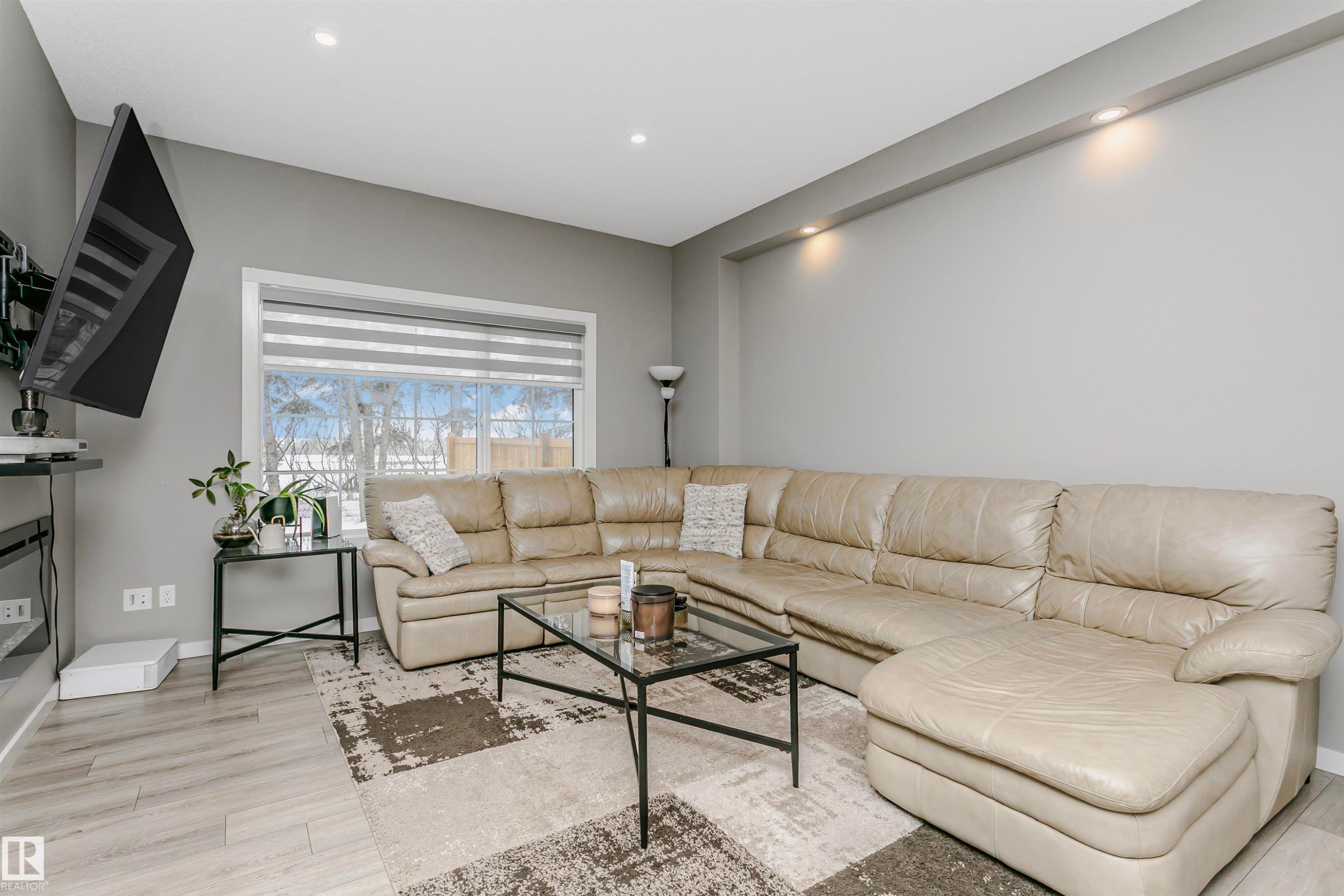 Living area featuring light wood-style floors, a glass covered fireplace, and recessed lighting - 7322 Chivers Crescent, Edmonton, AB - Indoor Photo Showing Living Room With Fireplace