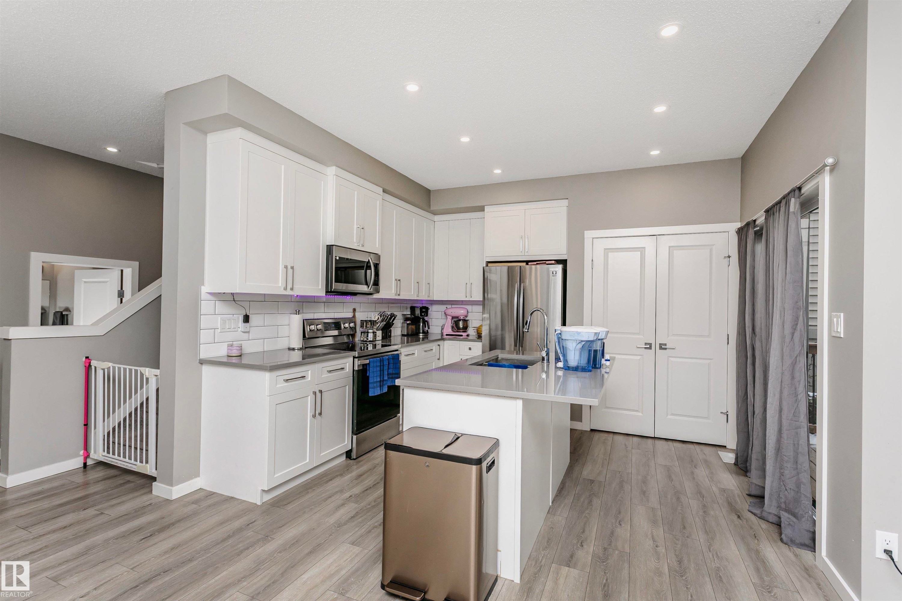 Kitchen with stainless steel appliances, white cabinetry, an island with sink, light wood-type flooring, and recessed lighting - 7322 Chivers Crescent, Edmonton, AB - Indoor Photo Showing Kitchen With Upgraded Kitchen