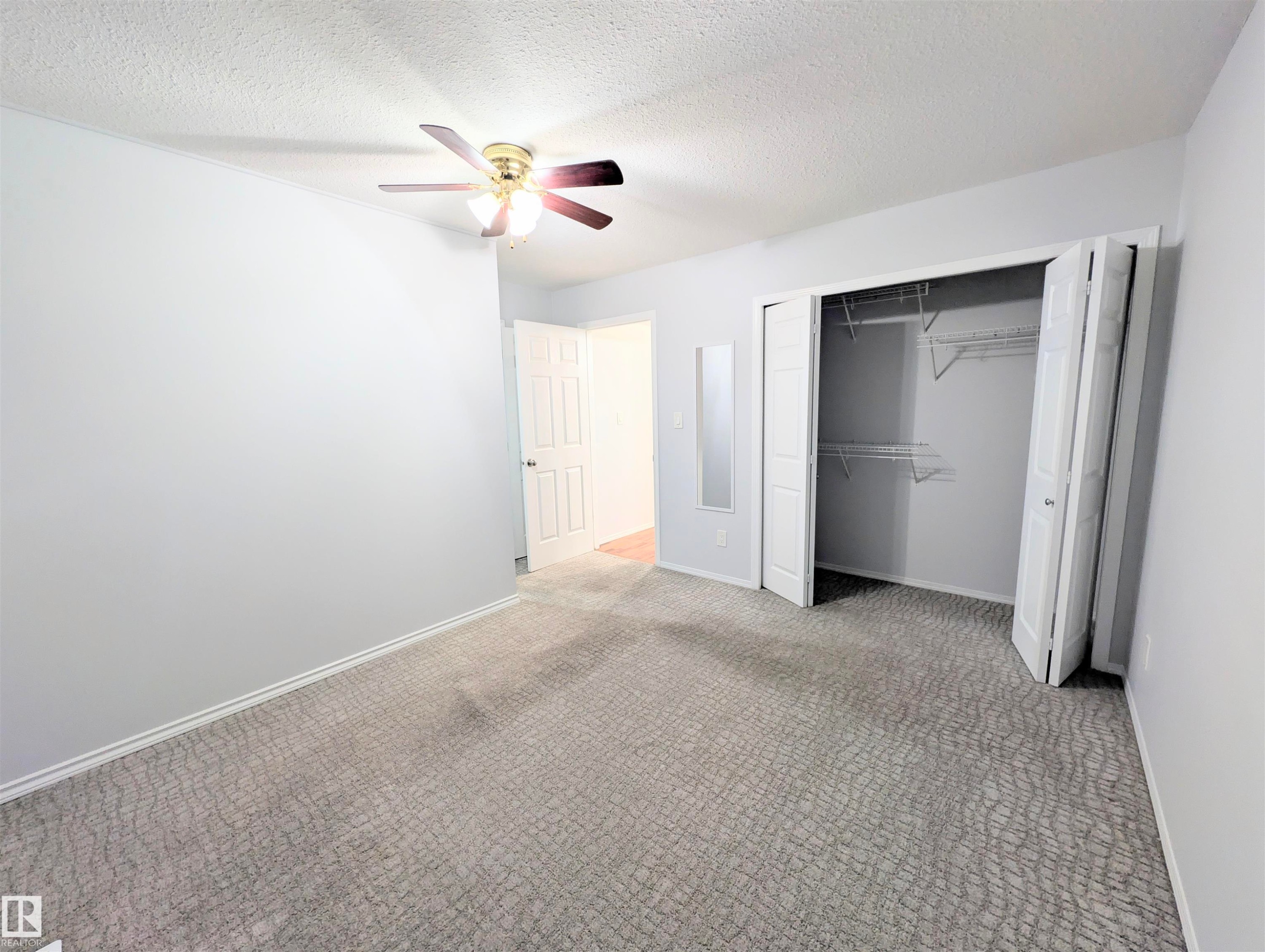 Unfurnished bedroom featuring carpet, a closet, a textured ceiling, and a ceiling fan - 3307 24 Avenue, Edmonton, AB - Indoor Photo Showing Other Room