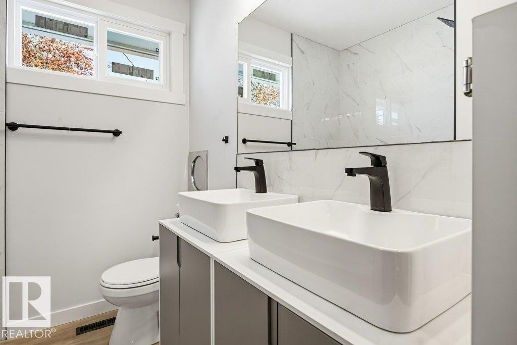 Bathroom with double vanity, a marble finish shower, and light wood-style floors - 7016 92A Avenue, Edmonton, AB - Indoor Photo Showing Bathroom