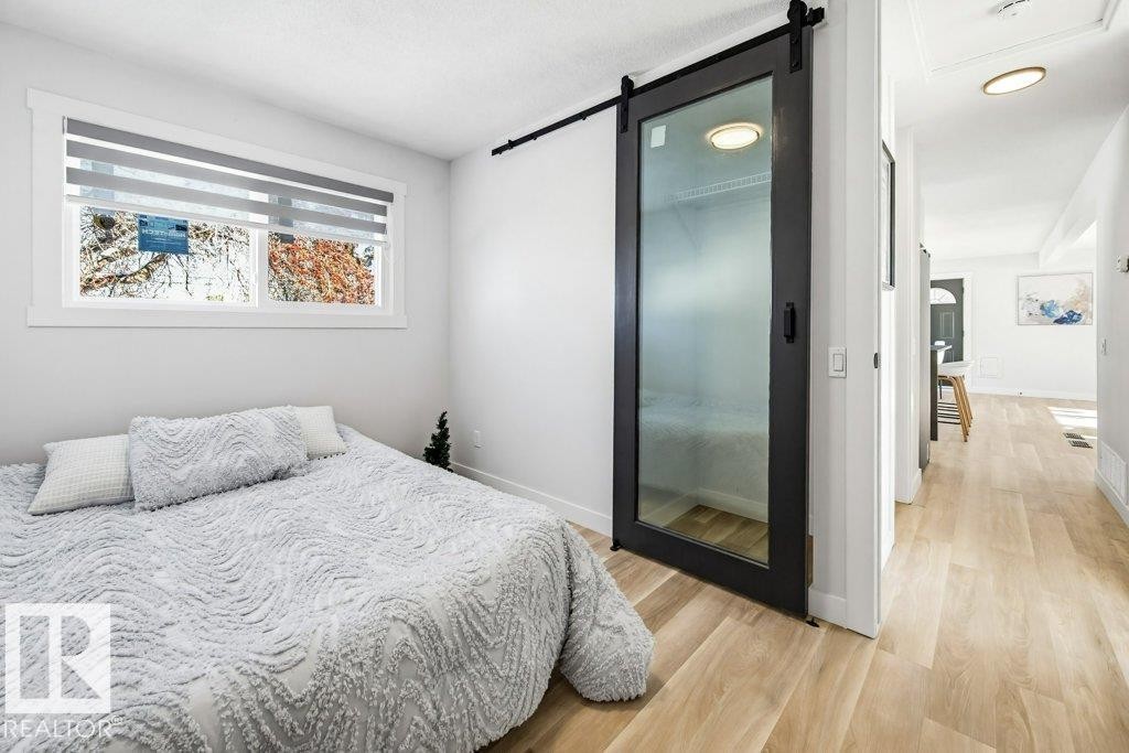 Bedroom with light wood finished floors and a barn door - 7016 92A Avenue, Edmonton, AB - Indoor Photo Showing Bedroom