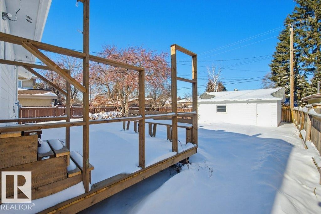Yard covered in snow with a wooden deck, a fenced backyard, and an outbuilding - 7016 92A Avenue, Edmonton, AB - Outdoor