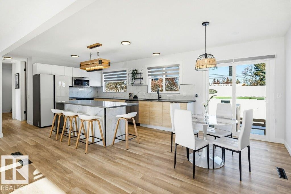 Kitchen with pendant lighting, modern cabinets, a kitchen island, and stainless steel appliances - 7016 92A Avenue, Edmonton, AB - Indoor