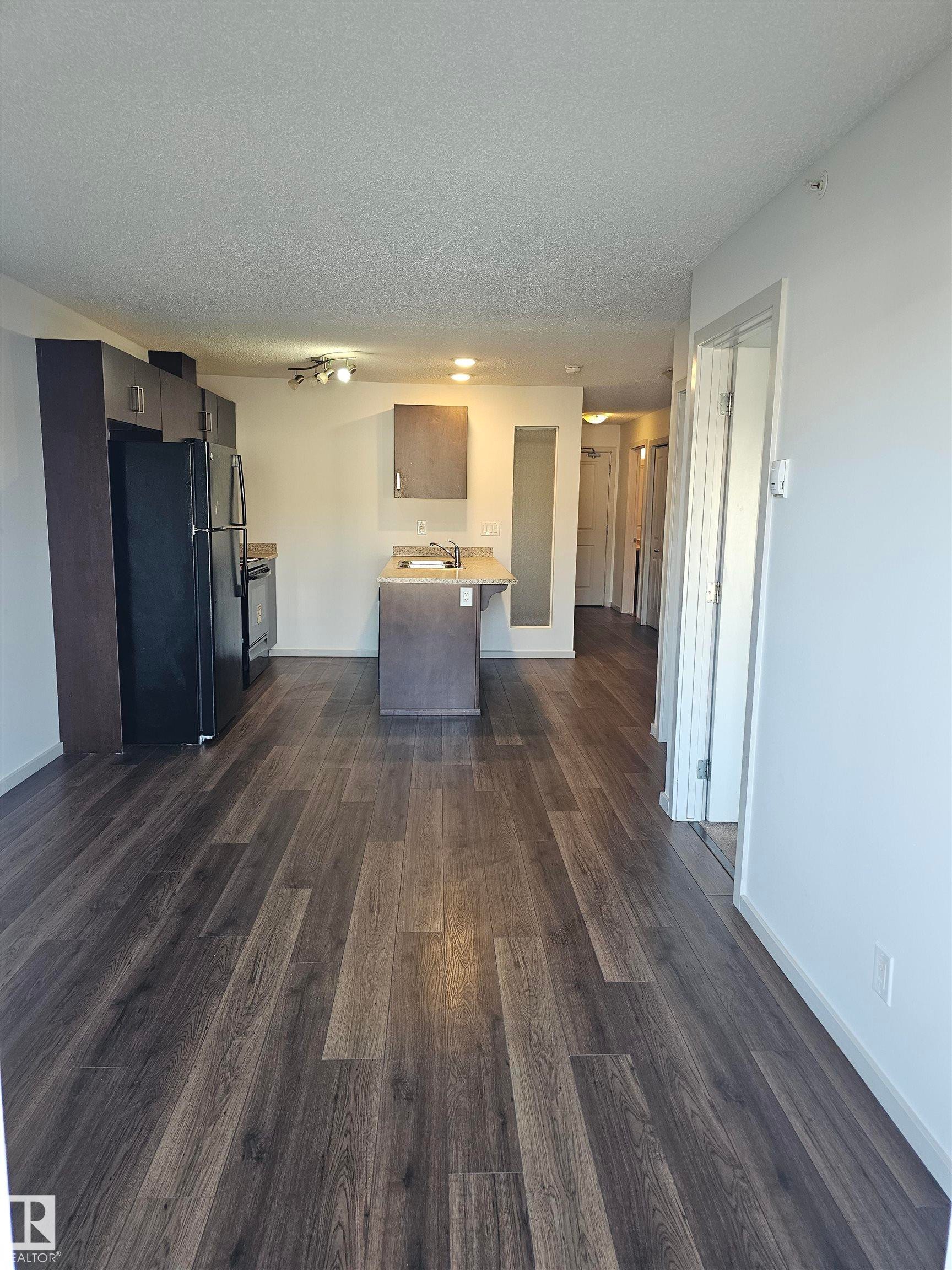 Kitchen featuring freestanding refrigerator, light countertops, a textured ceiling, dark wood-style flooring, and electric stove - 413 5521 7 Avenue, Edmonton, AB - Indoor