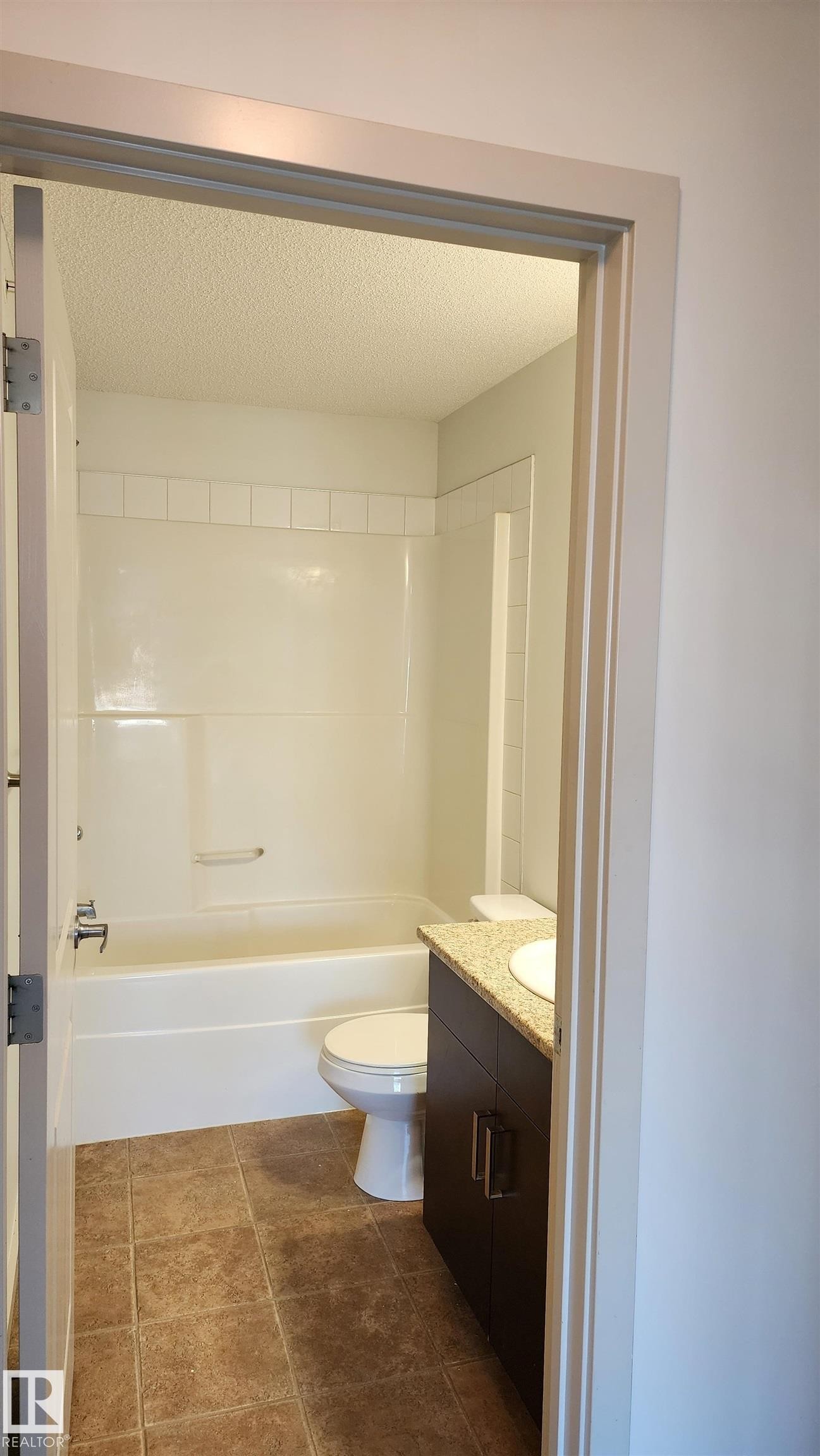 Full bath featuring vanity, bathing tub / shower combination, and a textured ceiling - 413 5521 7 Avenue, Edmonton, AB - Indoor Photo Showing Bathroom