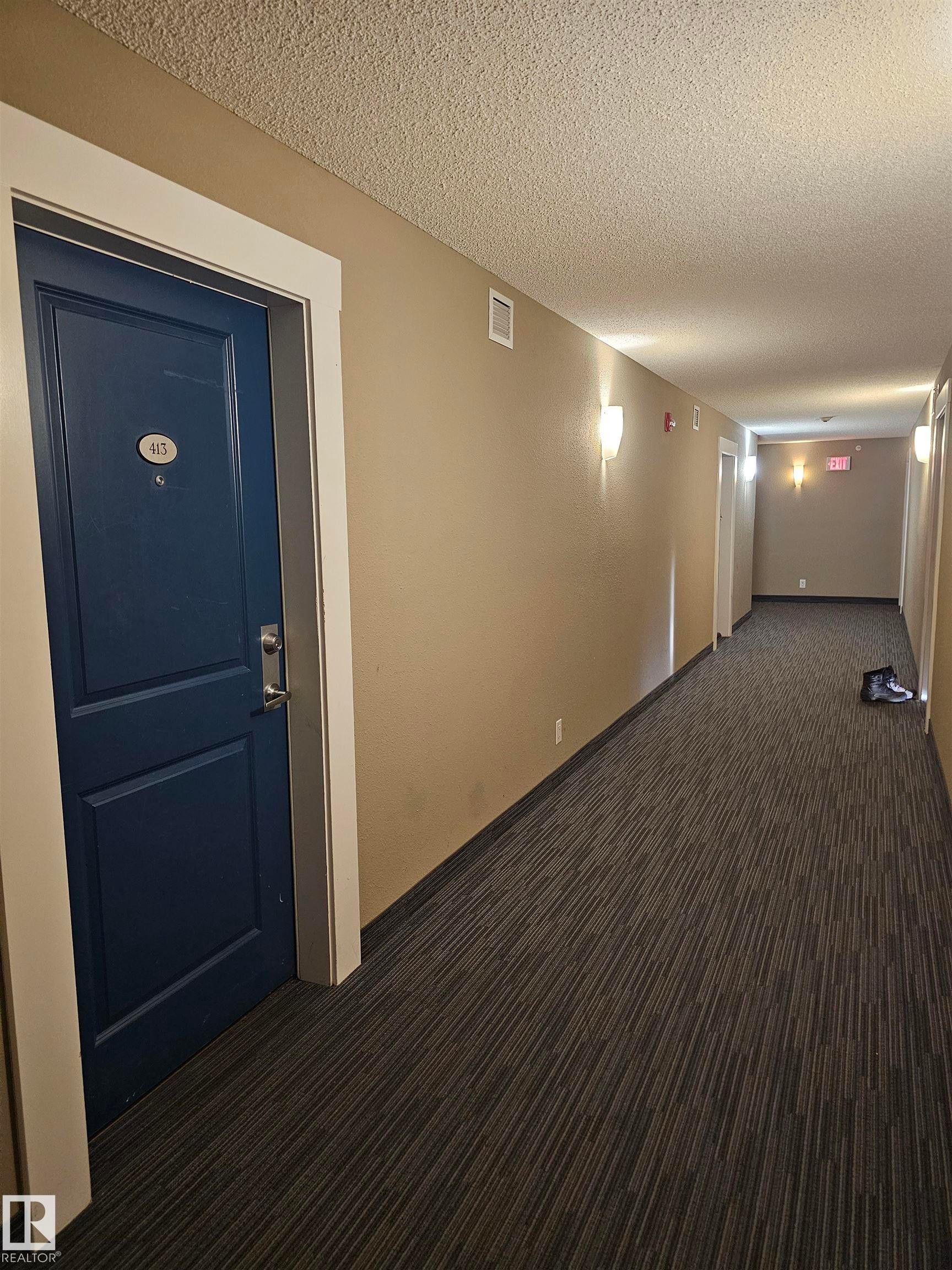 Corridor featuring a textured ceiling and dark colored carpet - 413 5521 7 Avenue, Edmonton, AB - Indoor Photo Showing Other Room