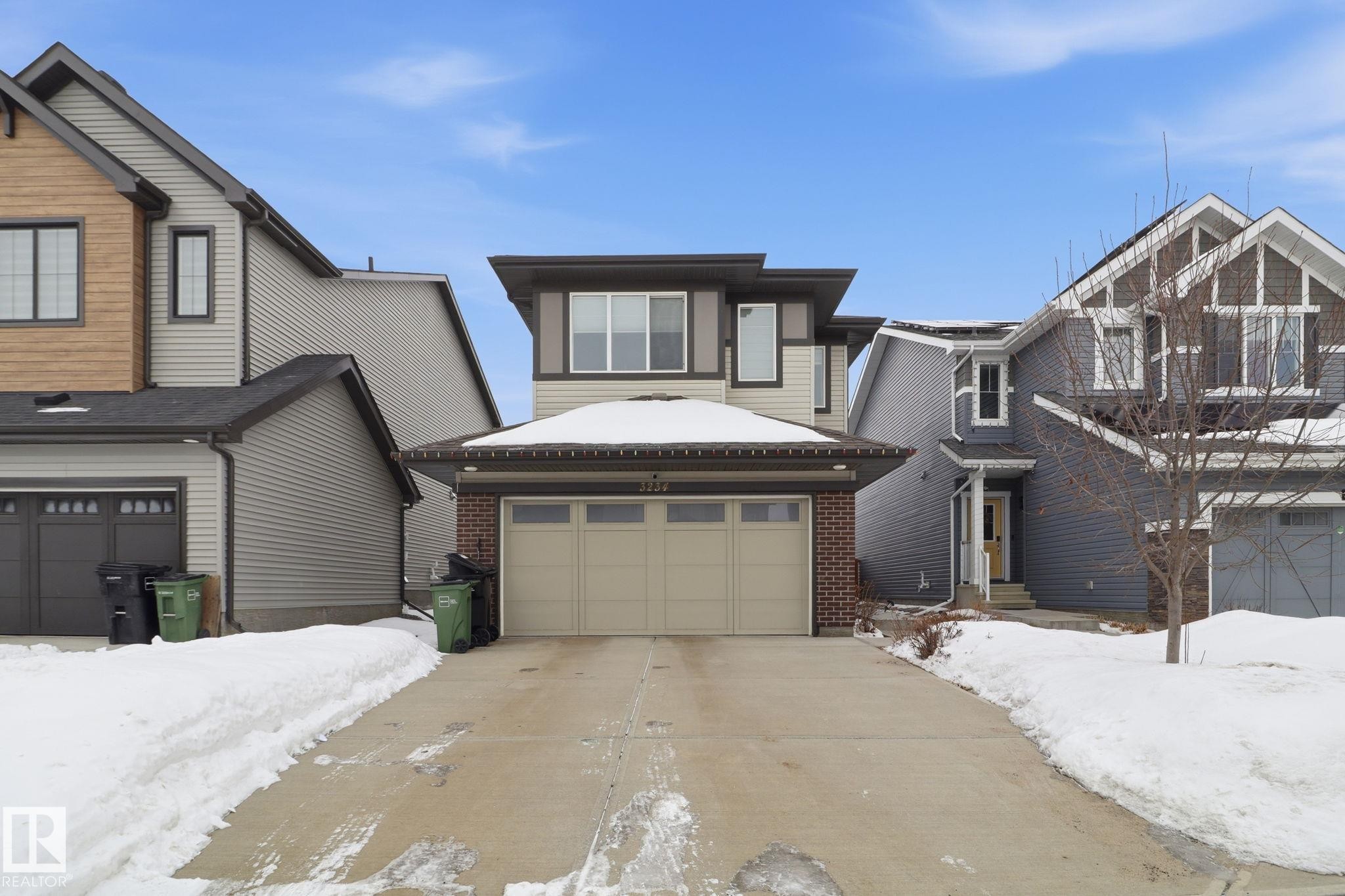 View of front facade with brick siding, an attached garage, and concrete driveway - 3234 Chernowski Way, Edmonton, AB - Outdoor With Facade