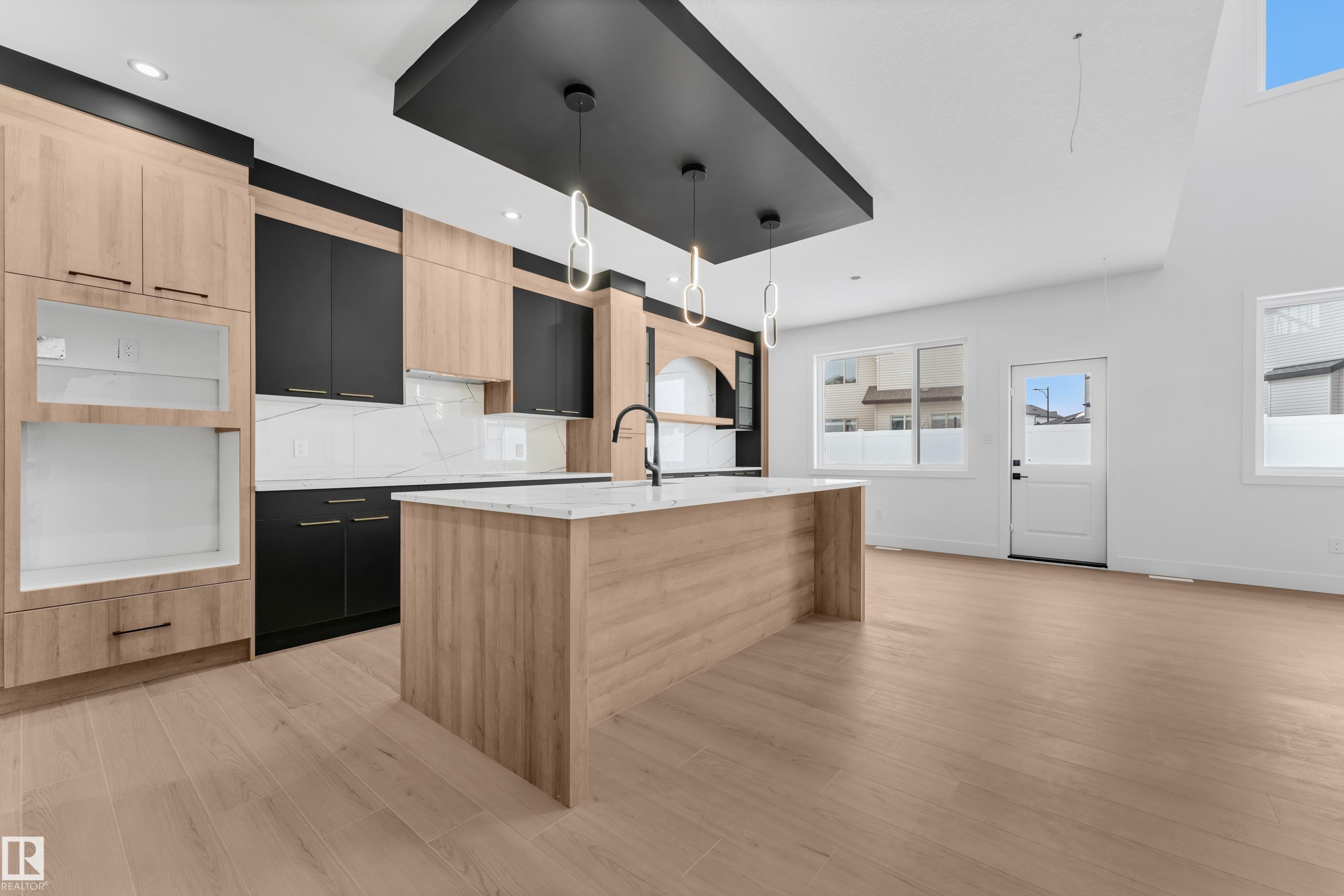Kitchen with dual tone cabinetry, light stone counters, an island with sink, hanging light fixtures, and modern cabinets - 741 Astoria Way, Devon, AB - Indoor Photo Showing Kitchen