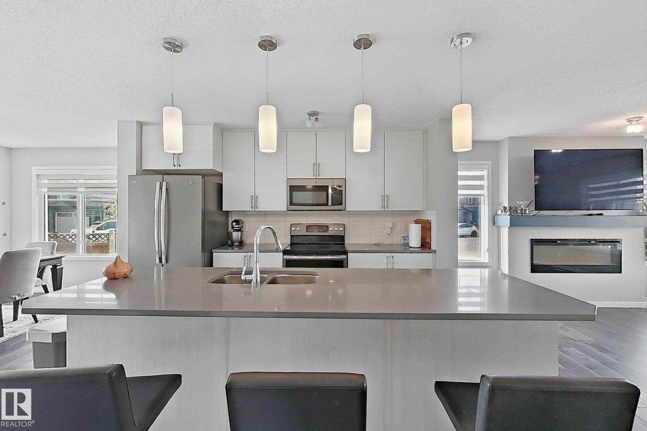 Kitchen featuring dark wood-style flooring, stainless steel appliances, backsplash, and pendant lighting - 4303 Prowse Link, Edmonton, AB - Indoor Photo Showing Kitchen With Double Sink With Upgraded Kitchen