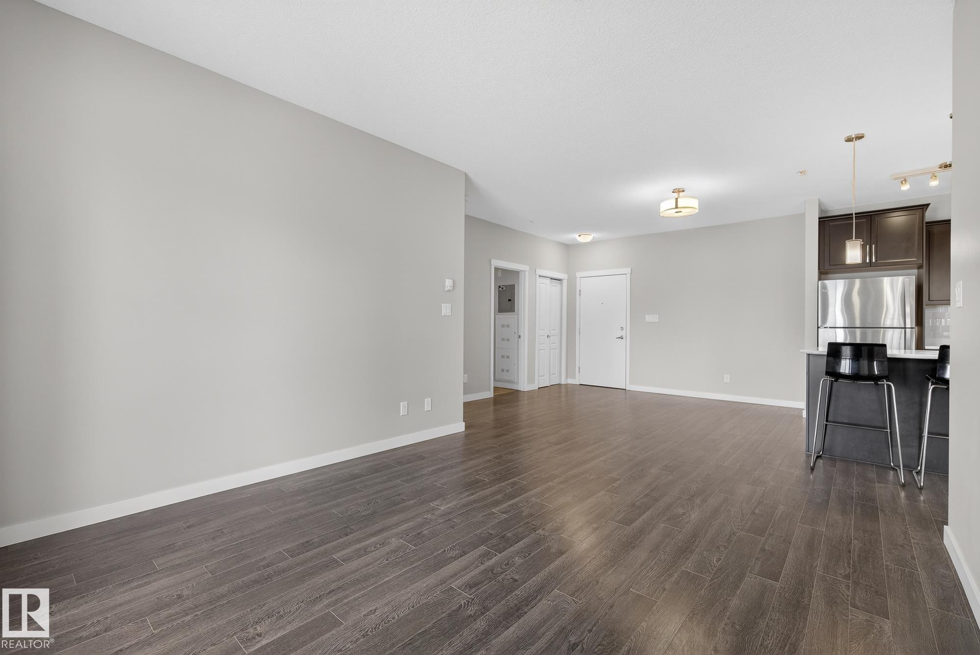 Unfurnished living room with dark wood-style floors and baseboards - 206 812 Welsh Drive, Edmonton, AB - Indoor