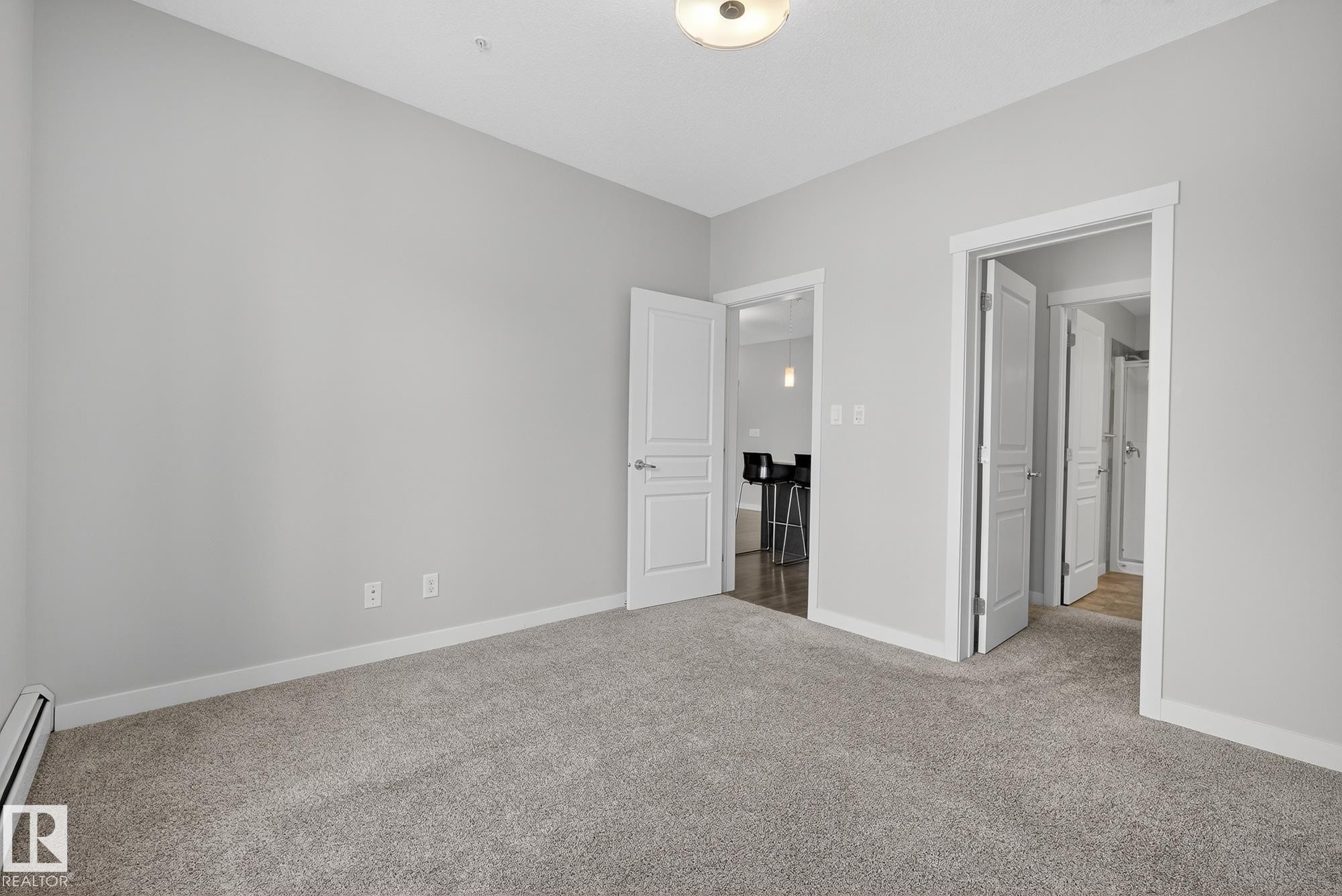 Unfurnished bedroom with carpet and a baseboard heating unit - 206 812 Welsh Drive, Edmonton, AB - Indoor Photo Showing Other Room