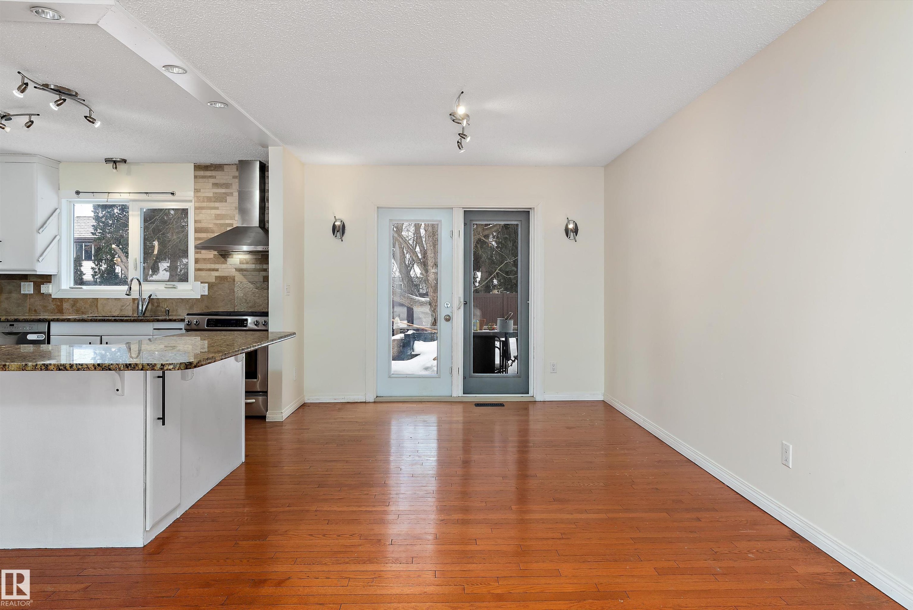 Kitchen with track lighting, dark stone counters, dark wood finished floors, stainless steel range, and white cabinetry - 115 Walker Road, Edmonton, AB - Indoor Photo Showing Kitchen