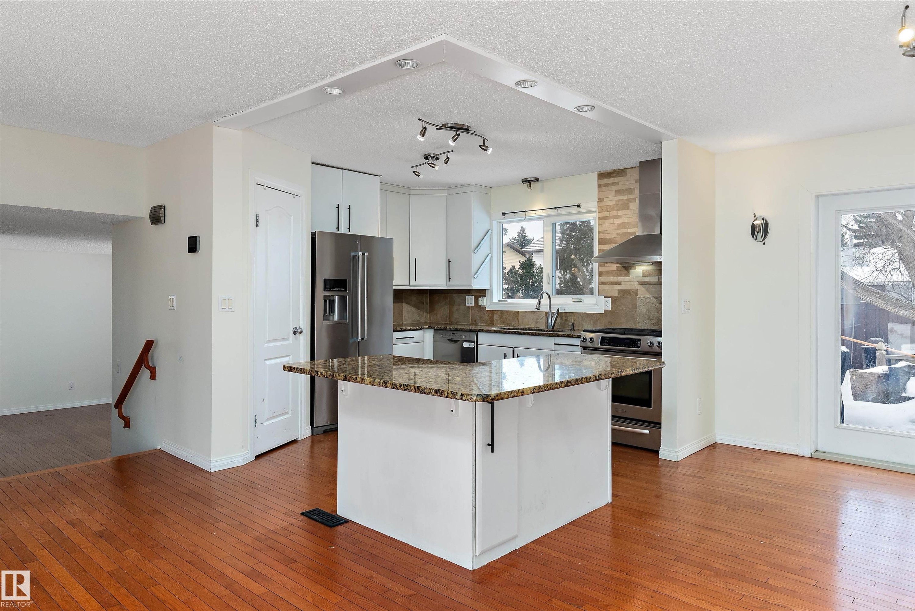 Kitchen featuring dark stone countertops, stainless steel appliances, dark wood-type flooring, white cabinets, and a textured ceiling - 115 Walker Road, Edmonton, AB - Indoor Photo Showing Kitchen With Upgraded Kitchen