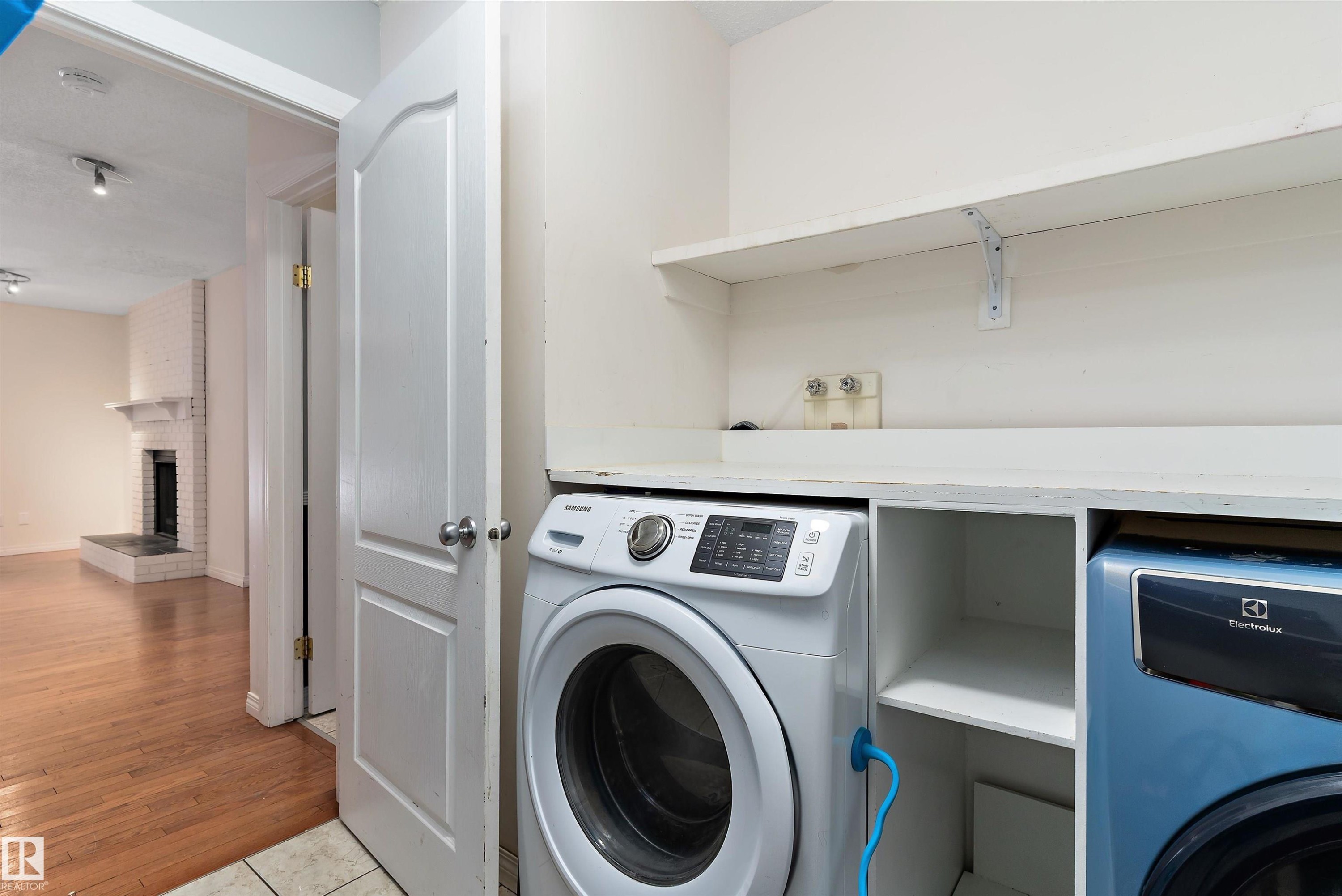 Laundry room with a brick fireplace and light wood-style flooring - 115 Walker Road, Edmonton, AB - Indoor Photo Showing Laundry Room