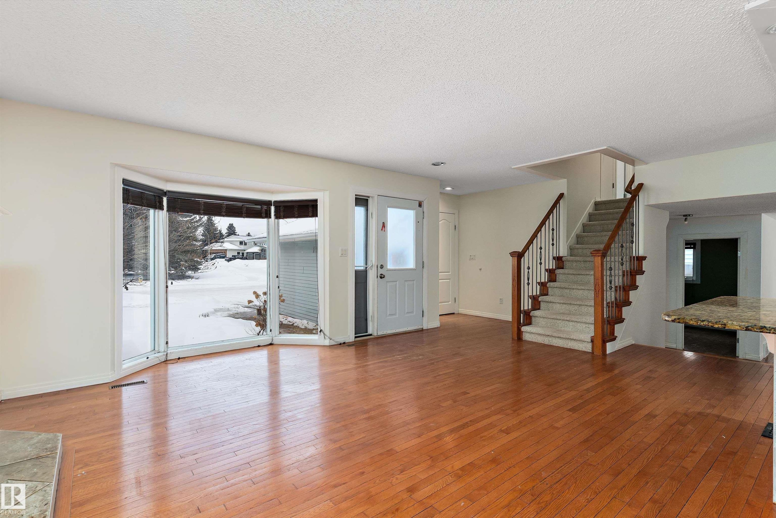 Unfurnished living room featuring light wood-style floors, healthy amount of natural light, and a textured ceiling - 115 Walker Road, Edmonton, AB - Indoor Photo Showing Other Room